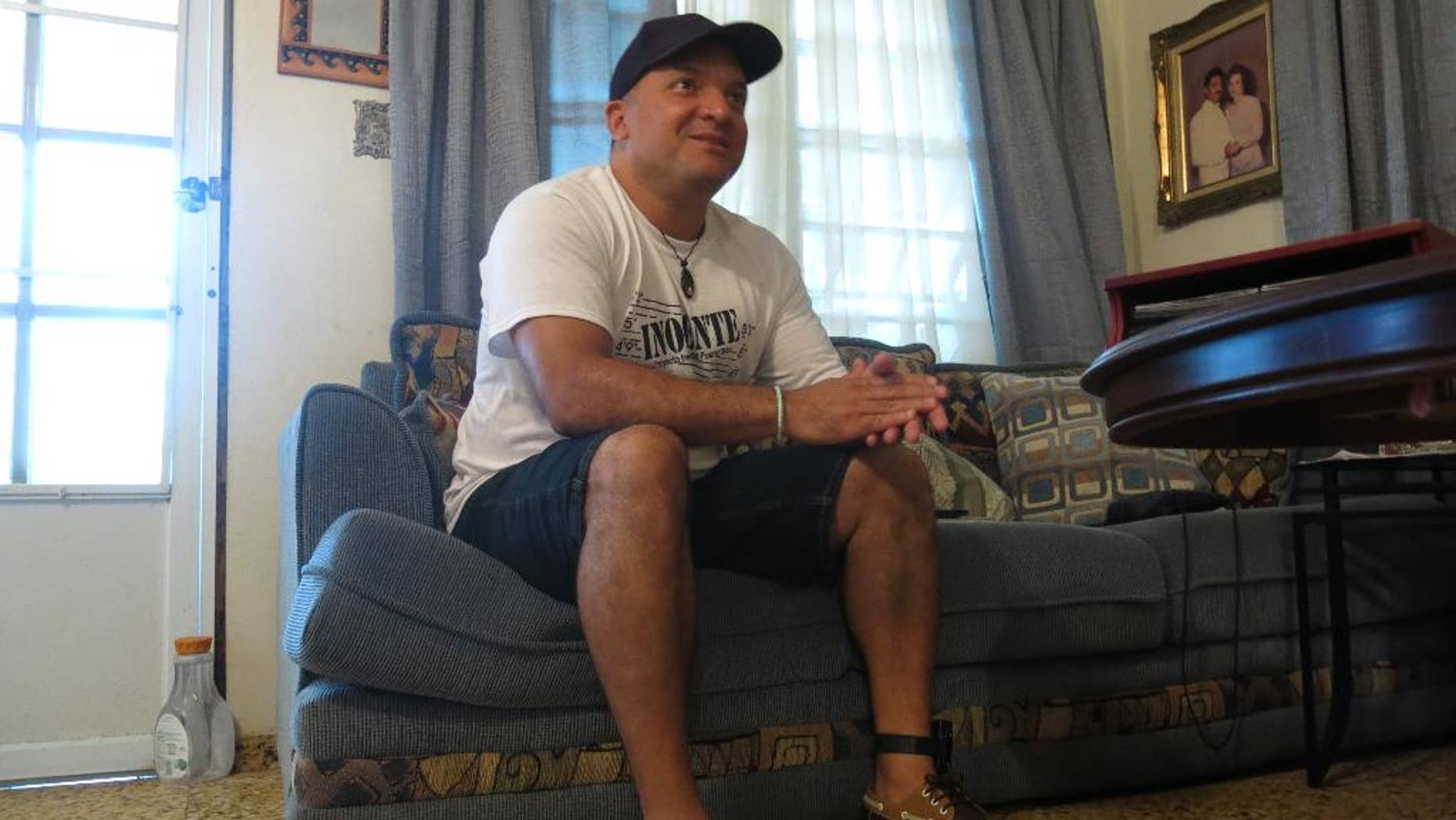 FILE - In this Aug. 6, 2016 file photo, Nelson Ortiz talks to a relative in Moca, Puerto Rico. Puerto Rico’s Justice Department has dropped charges on Tuesday, Sept. 27, 2016 against Ortiz and two other men who spent more than 20 years in prison for murder after new tests found none of their DNA on evidence in the case. They had been convicted in 1995 in the killing of 21-year-old pharmacy student Glorimar Perez. (AP Photo/Danica Coto, File)