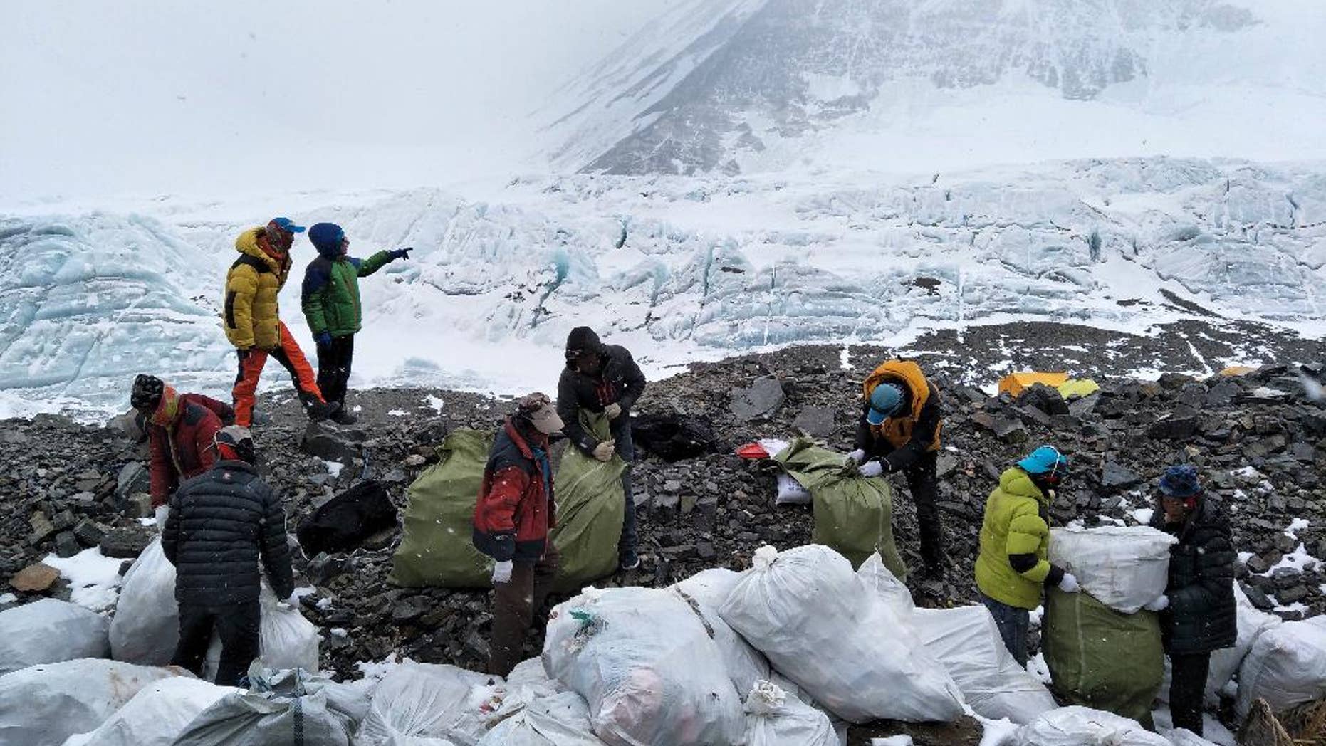 In this Monday, May 8, 2017 photo released by Xinhua News Agency, people collect garbage at the north slope of the Mount Qomolangma in southwest China's Tibet Autonomous Region. Workers and volunteers collected four tons of garbage from the Chinese north side of Mount Everest in the first five days of a cleanup operation.