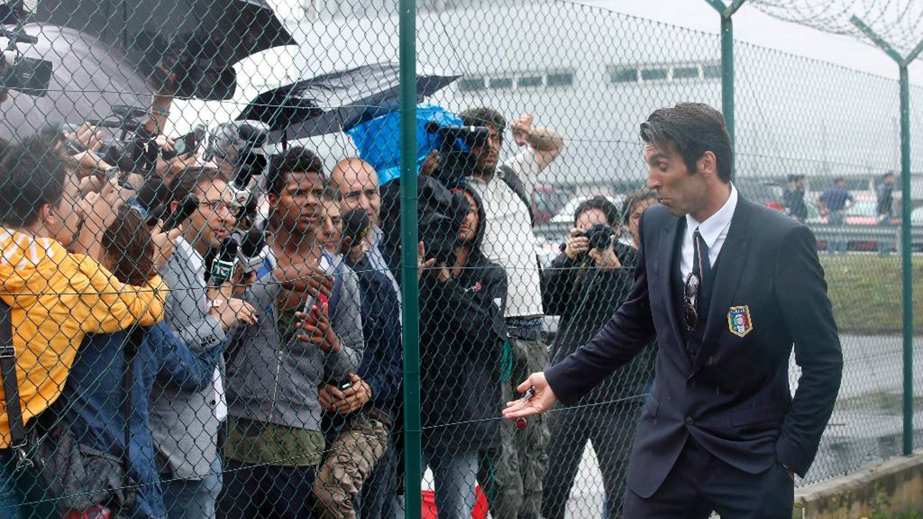 Italy goalkeeper Gianluigi Buffon talks to reporters upon his arrival with his teammates at Malpensa airport after landing from Brazil, in Milan, Italy, Thursday, June 26, 2014. Italy was disqualified from the World Cup after loosing to Uruguay in their group stage round. (AP Photo/Luca Bruno)