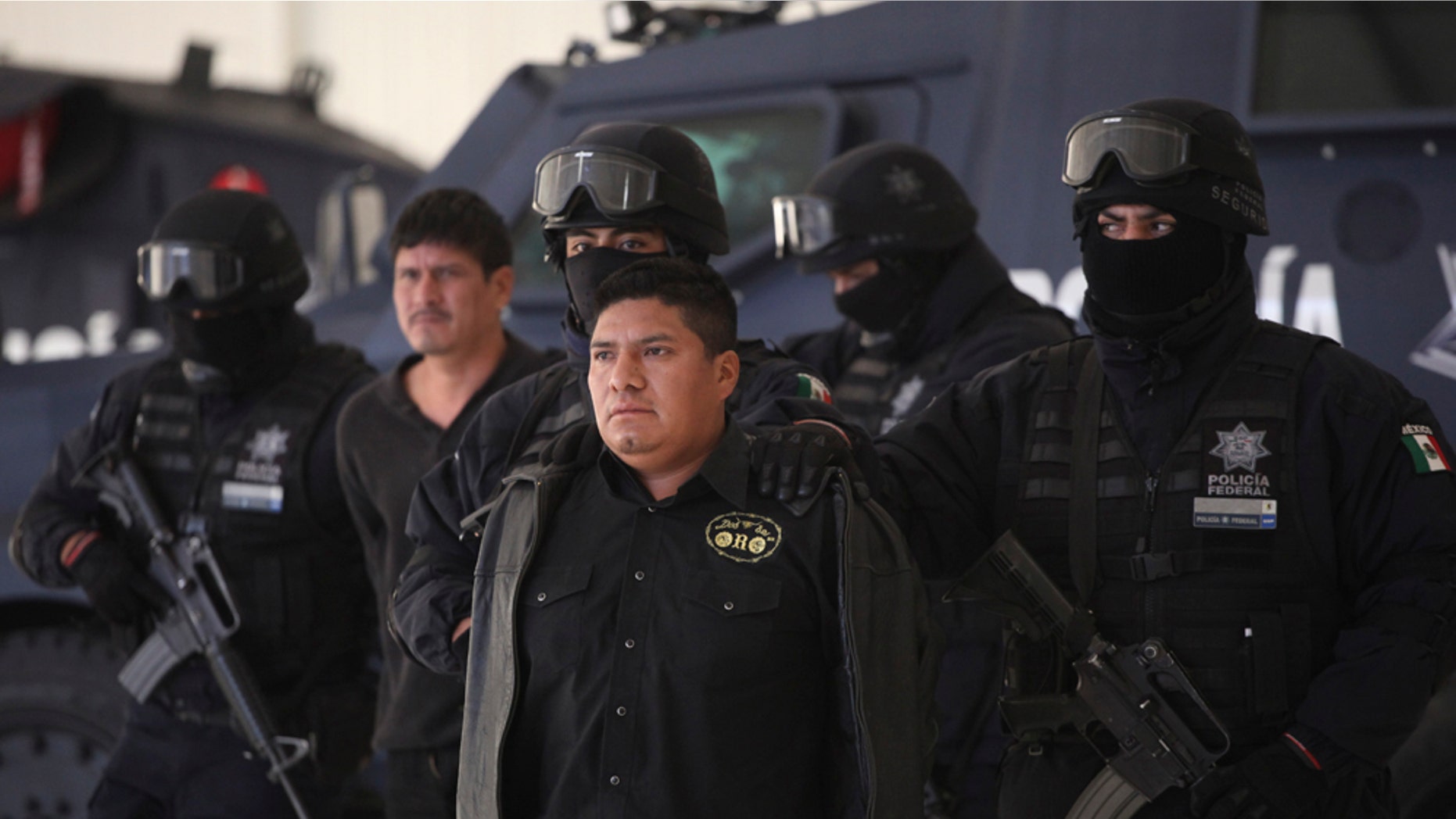 Federal Police agents escort Flavio Mendez Santiago, center, alias "El Amarillo," alleged member and co-founder of the Zetas drug cartel, during a presentation to the media in Mexico City, Tuesday, Jan. 18, 2011. Mendez Santiago was detained in Villa de Etla, Mexican state of Oaxaca, some 400 km southeast of Mexico City, on Monday. (AP Photo/Alexandre Meneghini)