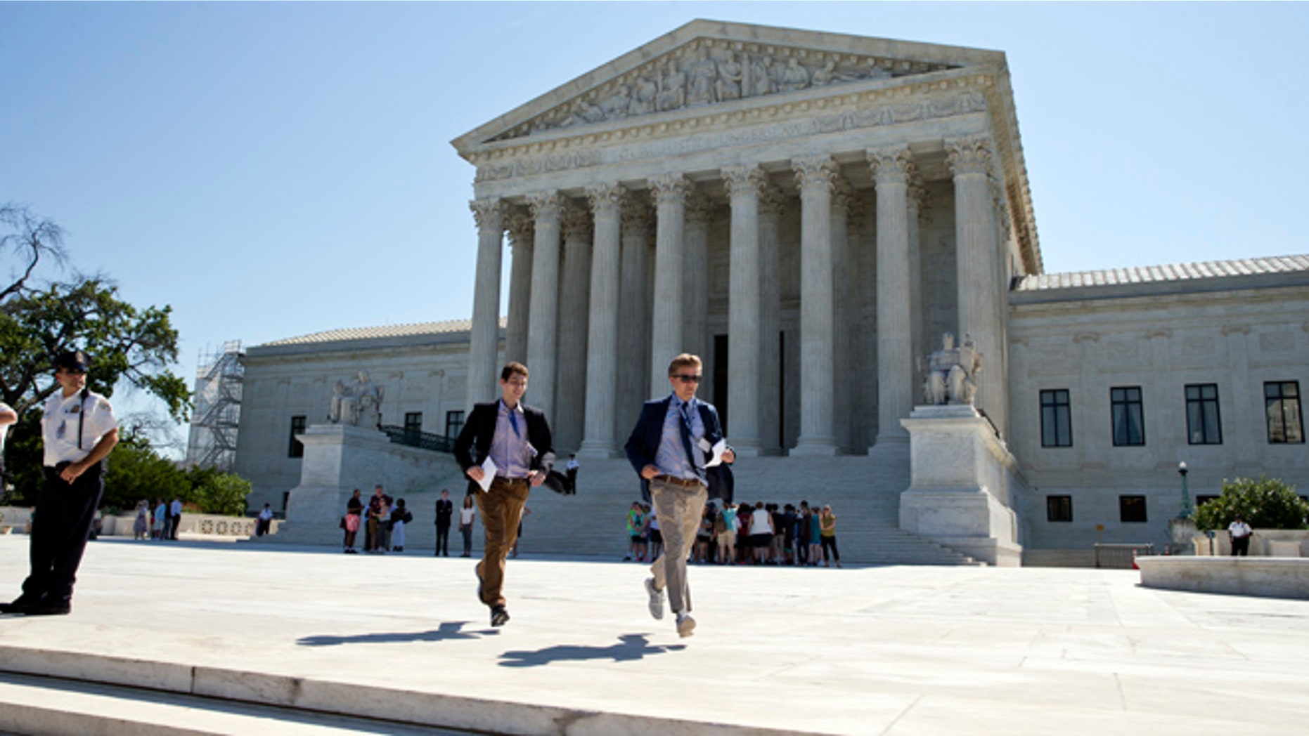 Gregory Briker, left, and John Bat, both with CBS News, run from the Supreme Court in Washington, Monday, June 20, 2016, with papers announcing court decisions. (AP Photo/Alex Brandon)