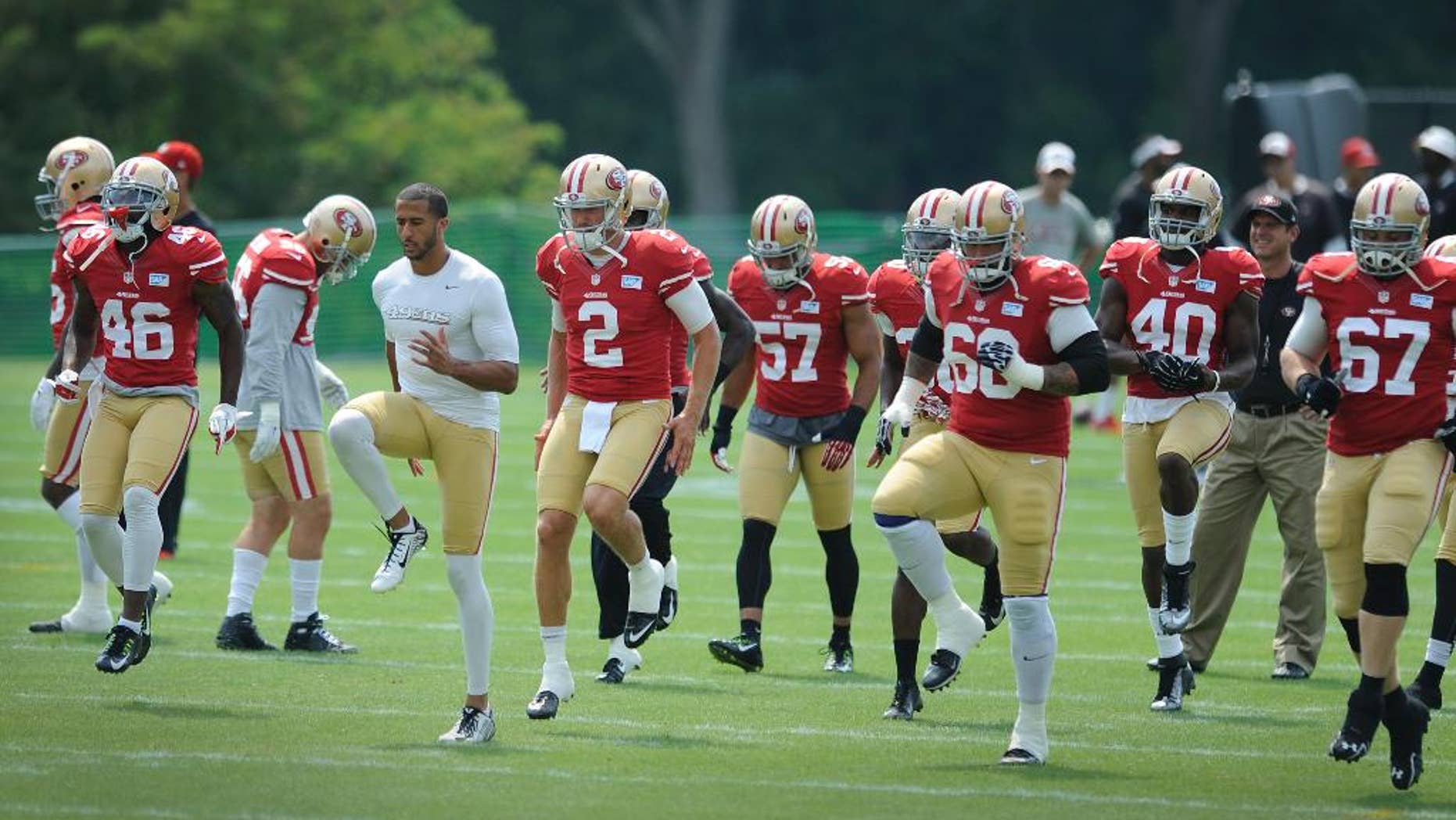 San Francisco 49ers quarterback Colin Kaepernick, in white shirt, leads his team in drills in a joint football practice with the Baltimore Ravens , Saturday, Aug. 9, 2014, in Owings Mills, Md.(AP Photo/Gail Burton)