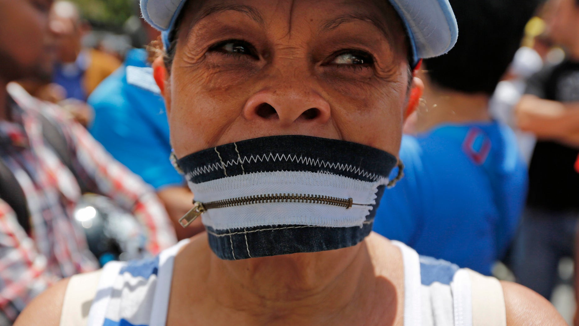 A protester wears a zipper over her mouth at a demonstration demanding the release of Metropolitan Mayor Antonio Ledezma in Caracas, Venezuela, Friday, Feb. 20, 2015. Demonstrators are condemning last night's surprise arrest of the Caracas' mayor for allegedly plotting to overthrow the government of President Nicolas Maduro. Late Thursday Maduro said that Ledezma, one of the most vocal opposition leaders, would be punished for trying to sow unrest in Venezuela. (AP Photo/Ariana Cubillos)