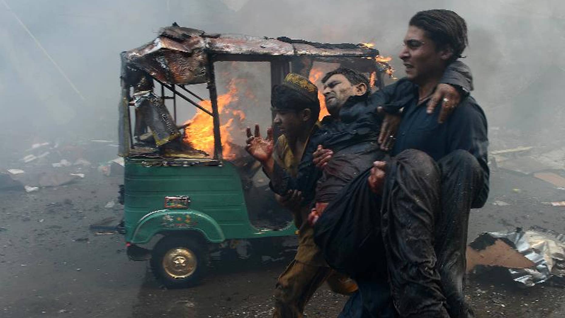 Pakistani men carry an injured blast victim at the site of a bomb explosion in the busy Kissa Khwani market in Peshawar on September 29, 2013