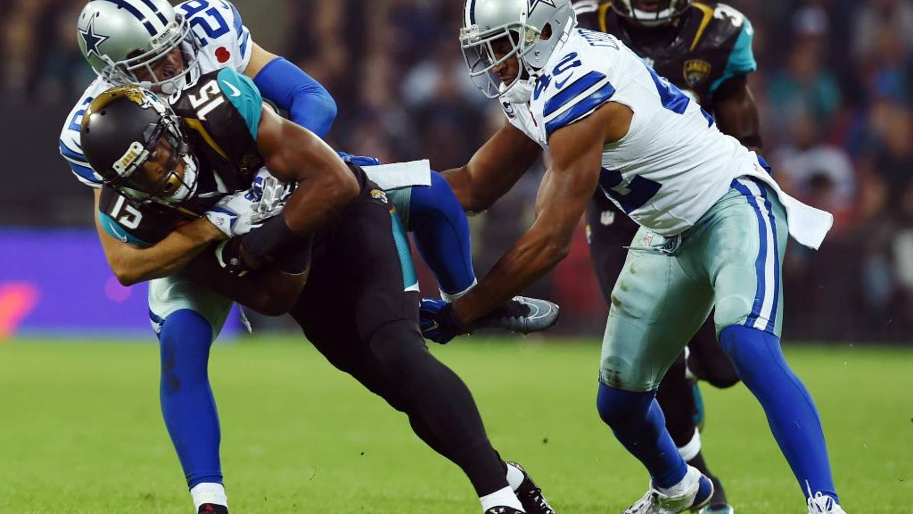 Jacksonville Jaguars wide receiver Allen Robinson (15) is tackled by Dallas Cowboys defensive back Sterling Moore (26) and strong safety Barry Church (42) during the first half of an NFL football game at Wembley Stadium, London, Sunday, Nov. 9, 2014. (AP Photo/Matt Dunham)