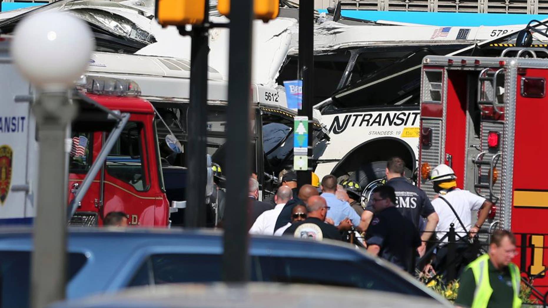 Police, firefighters and EMS personnel work at the scene on Broad Street after two commuter buses collided in Newark, N.J., Friday, Aug. 19, 2016. Investigators are trying to determine if a commuter bus ran a red light and broadsided another commuter bus, killing a driver and injuring several. (AP Photo/Mel Evans)