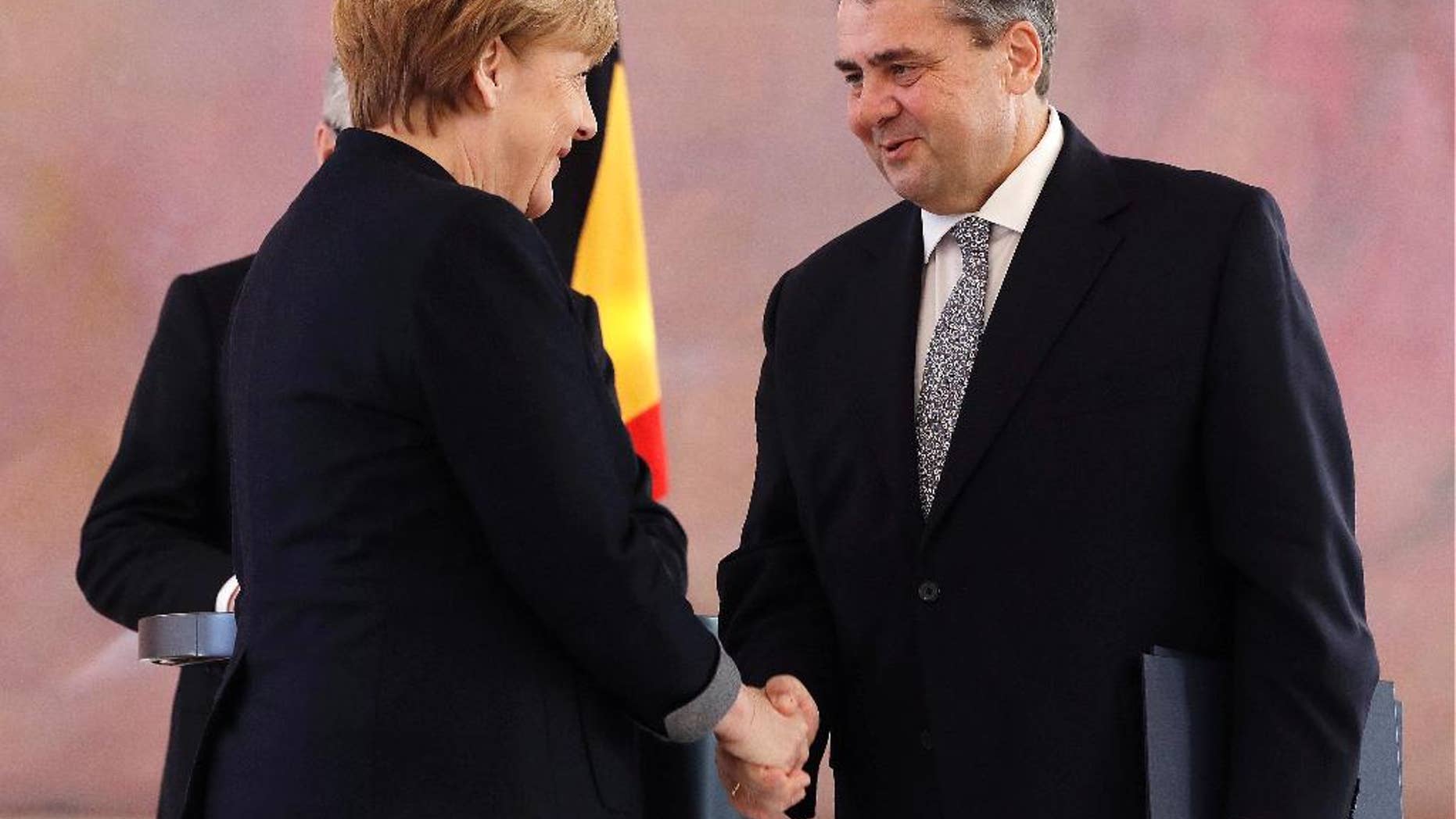 Former German Minister for Economic Affairs and Energy and new Foreign Minister Sigmar Gabriel shakes hands with German Chancellor Angela Merkel after he received his notices of dismissal and documents of appointment by German President Joachim Gauck in Berlin, Germany, Friday, Jan. 27, 2017. (AP Photo/Michael Sohn)