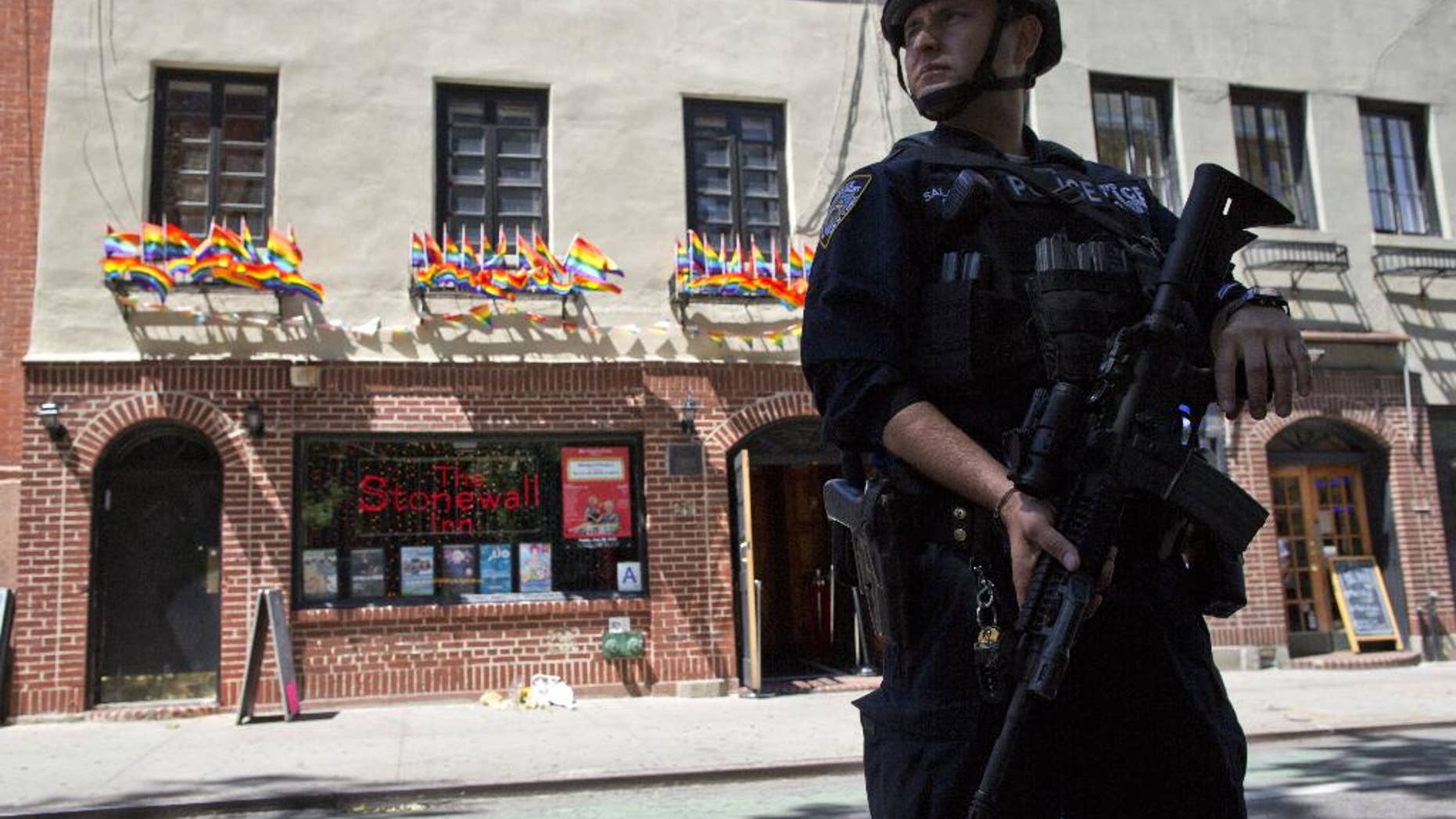 FILE - In a June 12, 2016 file photo, an armed police officer stands guard outside the Stonewall Inn, in New York. Sunday's mass shooting the Pulse nightclub, in which gunman Omar Mateen killed dozens of people before dying in a gun battle, prompted an outpouring of reminiscence and reflection on that vital roles that such clubs have played for many lesbians, gays, bisexuals and transgender people across the U.S. (AP Photo/Mary Altaffer, File)