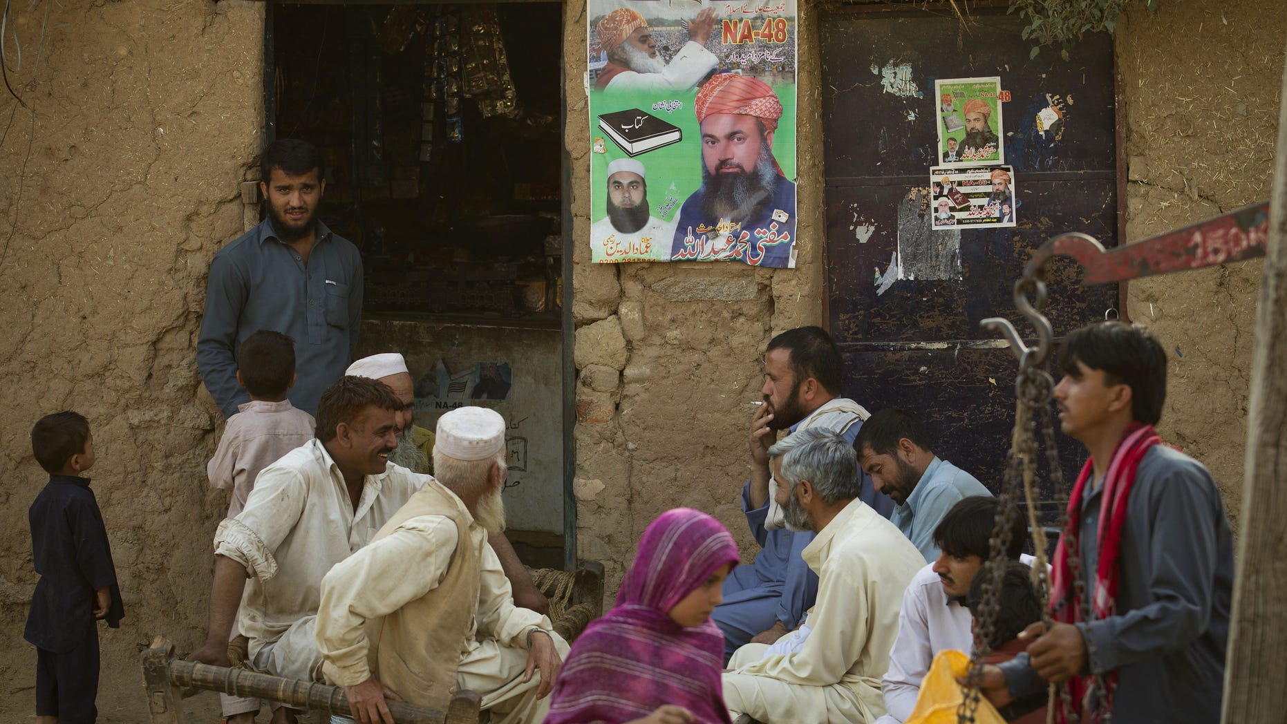 People sit outside a campaign office of a candidate in Pakistan's nationwide elections in Islamabad's slums on Tuesday, May 14, 2013 in Pakistan. The final vote count from weekend's nationwide elections in Pakistan on Tuesday confirmed a big win for former Prime Minister Nawaz Sharif's party. (AP Photo/B.K. Bangash)