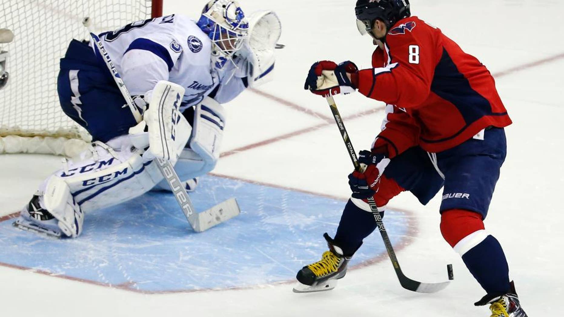Washington Capitals right wing Alex Ovechkin, right, from Russia, shoots the puck behind his back against Tampa Bay Lightning goalie Anders Lindback, from Sweden, in the shootout portion of an NHL hockey game on Sunday, April 13, 2014, in Washington. Lindback blocked the shot and the Lightning won 1-0 in a shootout. (AP Photo/Alex Brandon)