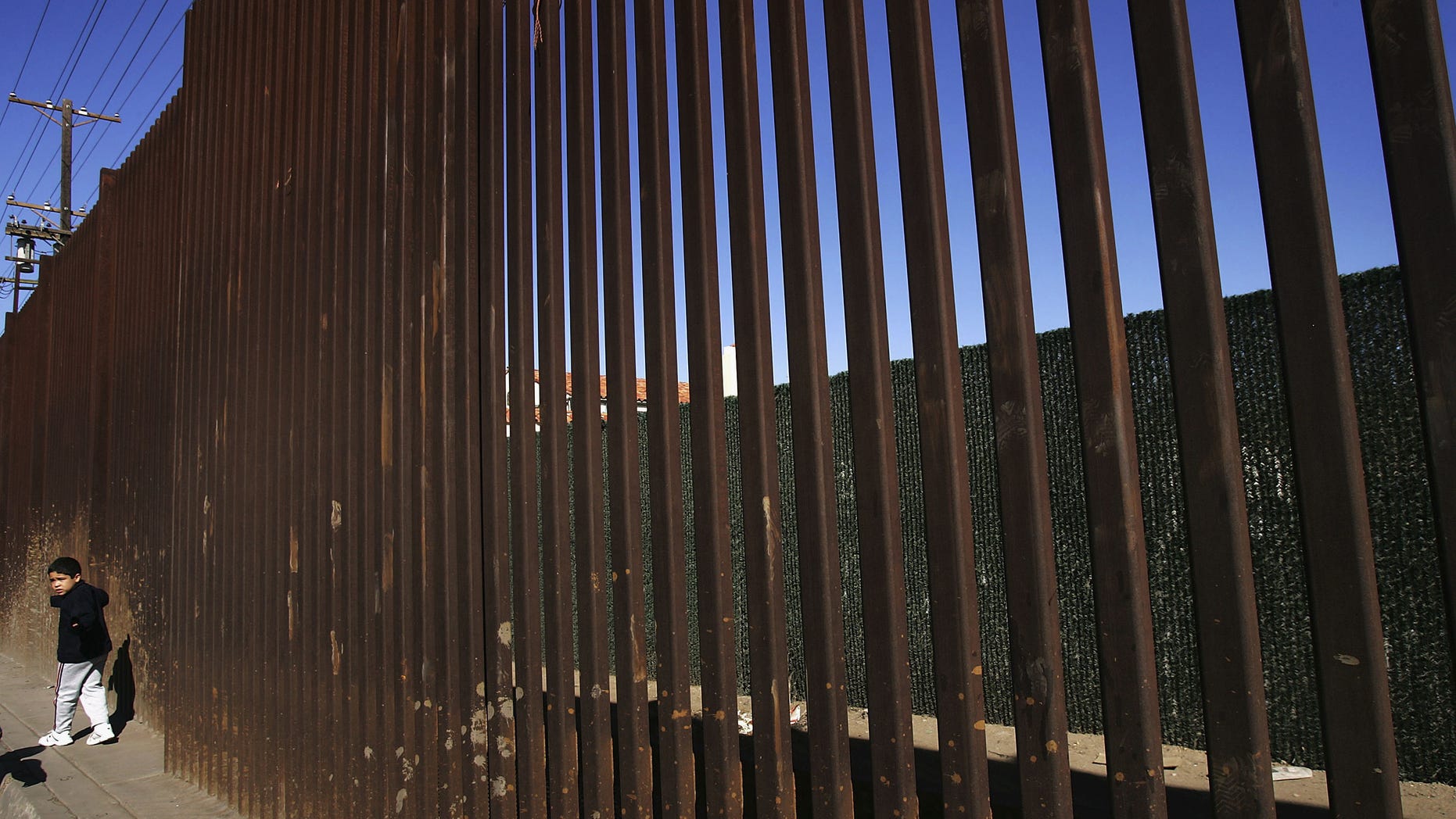 MEXICALI, BAJA CALIFORNIA - MARCH 25: A boy walks along the US/Mexico border fence on March 25, 2005 in Mexicali, Baja California, Mexico. Since the launch of the North American Free Trade Agreement in 1995, two-way trade has boomed between the US and Mexico, and Mexican dollars are fueling development in economically-depressed Calexico, California. Border communities are now growing increasingly worried that the recent economic gains may be lost as the Bush administration's efforts to tighten security in order to prevent terrorists or their weapons from crossing the border could slow the wheels of commerce. (Photo by David McNew/Getty Images)