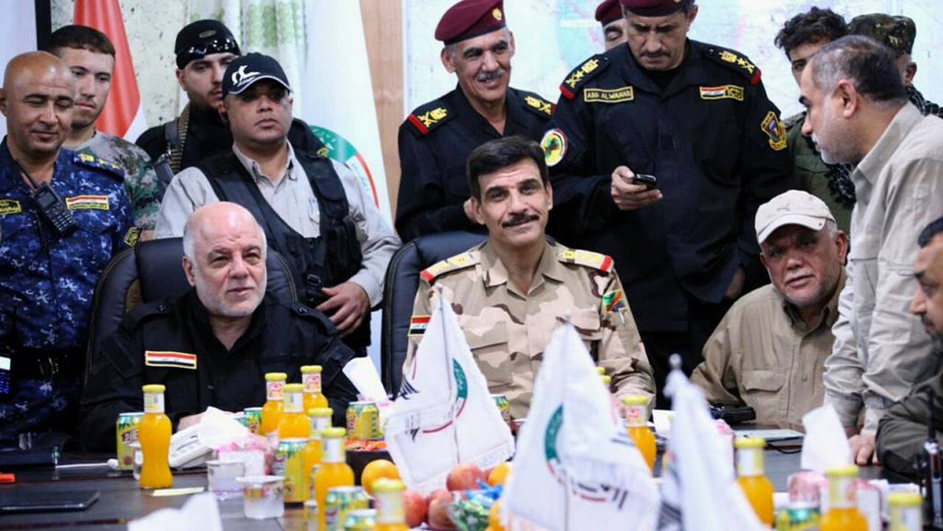 This picture provided by the office of Iraq's Prime Minister, shows Iraqi Prime Minister Haider al-Abadi, seated left, wearing a black uniform and flanked by senior military commanders during a meeting at the Fallujah Operation Command center outside Fallujah, Iraq, Monday, May 23, 2016. Iraqi government forces on Monday pushed Islamic State militants out of some agricultural areas outside Fallujah as they launched a military offensive to recapture the city from the extremists, officials said. (Iraqi Prime Minister's Office via AP)
