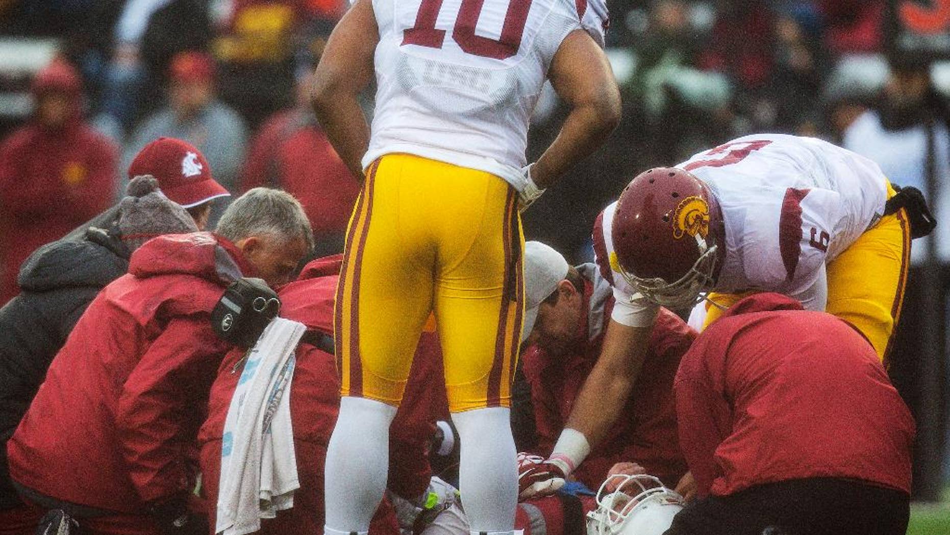 Southern California team captains linebacker Hayes Pullard (10) and quarterback Cody Kessler (6) check on injured Washington State quarterback Connor Halliday (12) during the first quarter of an NCAA college football game, Saturday, Nov. 1, 2014, at Martin Stadium in Pullman, Wash. Halliday was taken off the field and transported to at Pullman Regional Hospital in Pullman with a splint on his right leg. (AP Photo/Dean Hare)
