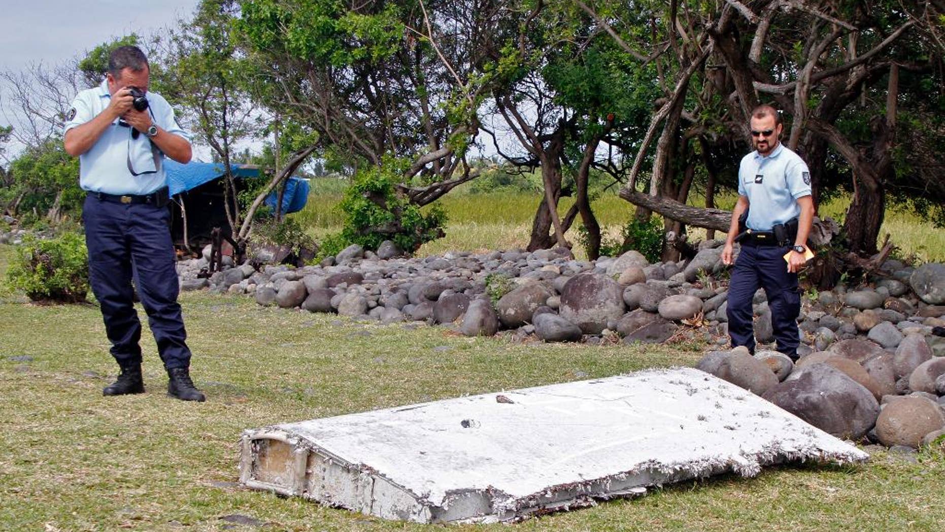 FILE - In this July 29, 2015 file photo, French police officers look over a piece of debris from a plane in Saint-Andre, Reunion Island. The wing was later found to be from missing Malaysia Airlines Flight 370 that went missing March 8, 2014, with 239 people aboard while flying from Kuala Lumpur to Beijing. Analysis of a genuine Boeing 777 wing flap has reaffirmed experts' opinion that a missing Malaysian airliner most likely crashed north of an abandoned search area in the Indian Ocean, officials said Friday, April 21, 2017. The search for Malaysia Airlines Flight 370 ended in January after a deep-sea sonar scan failed to find any trace of the plane. But research has continued in an effort to refine a possible new search. (AP Photo/Lucas Marie, File)