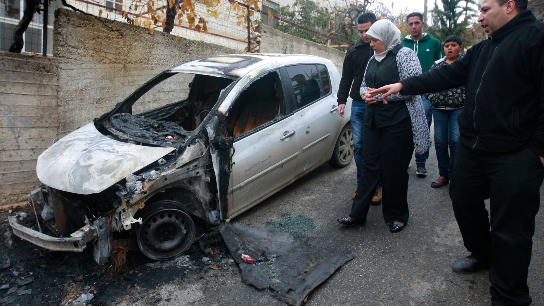 Palestinian Dr. Laila Ghannam, the governor of Ramallah and al-Bireh, inspects an area attacked by suspected Jewish settlers in the Jalazoun refugee camp north of Ramallah, Tuesday, Dec. 31, 2013. Israeli police say suspected Jewish vandals set fire to three vehicles in the West Bank early Tuesday and sprayed threatening graffiti referencing U.S. Secretary of State John Kerry ahead of his expected visit to the region this week. (AP Photo/Majdi Mohammed)