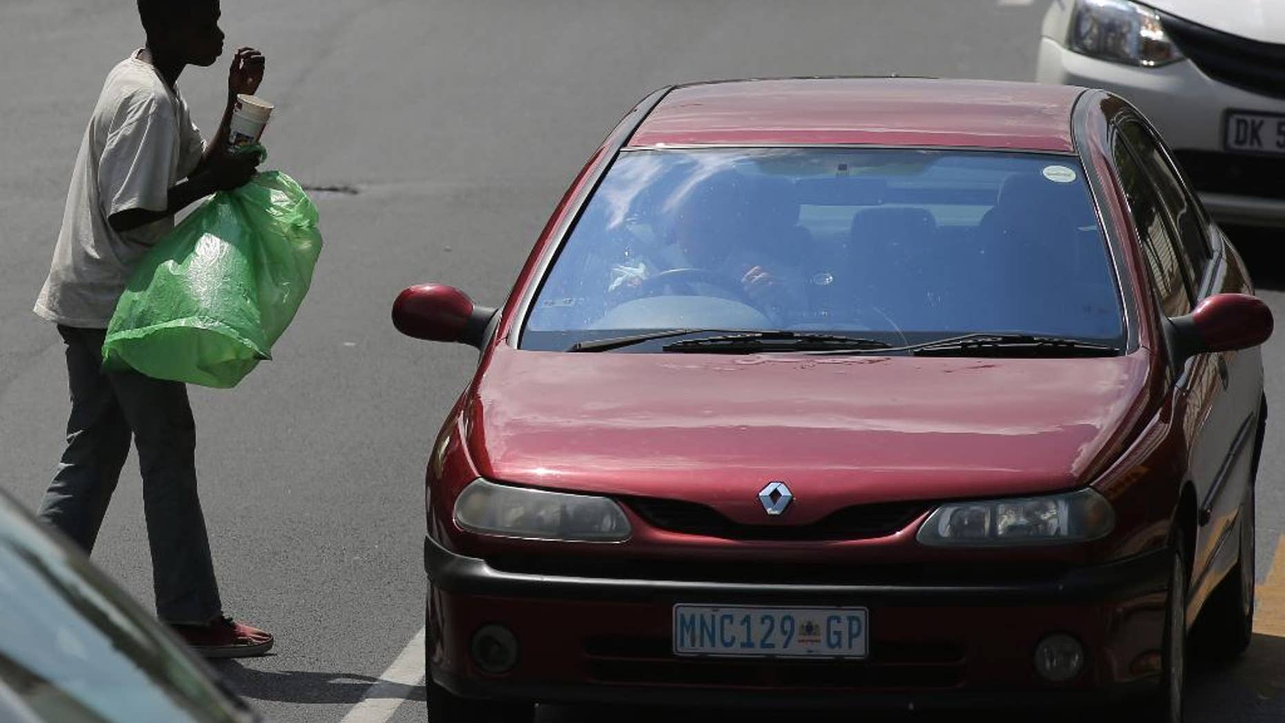 In this photo taken Wednesday, March 16, 2016, a man begs from passing motorists at a busy intersection in Johannesburg. The South African government said Monday, May 9, 2016 that the struggling economy, one of Africa's biggest, is poised for a turnaround after years of slow growth, even though severe challenges remain. (AP Photo/Denis Farrell)