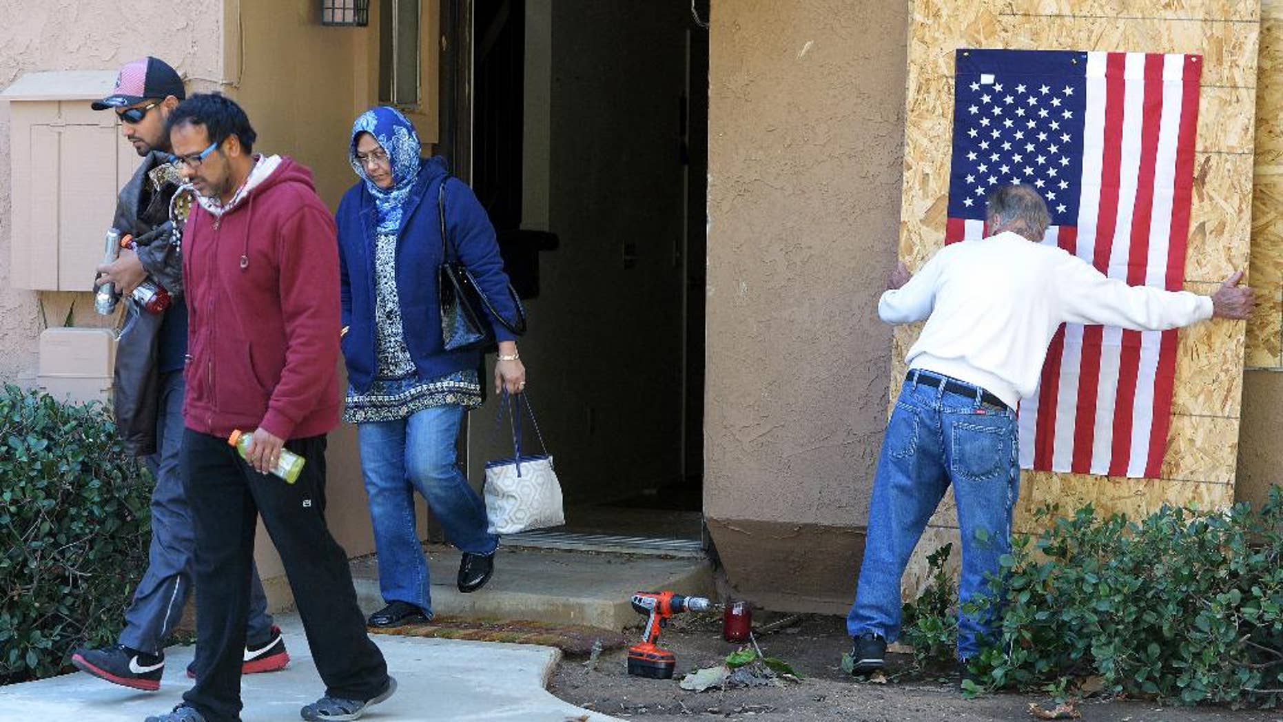FILE - In this Dec. 19, 2015, file photo, Syed Rizwan Farook's brother Syed Raheel Farook, left, brother-in-law Farhan Khan, second from left, and mother, Rafia Farook, third from left, leave the house of the husband and wife who killed 14 people in San Bernardino, Calif., as landlord Doyle Miller prepares to board up the property in Redlands, Calif. The family was removing items from the couple's home. Since the attack, Rafia Farook, 62, has emerged as a mysterious figure; someone close to her son, yet according to family attorneys utterly unaware of his terrorist plans or that he had turned the townhome garage in a makeshift bomb-making facility. (Will Lester/The Inland Valley Daily Bulletin via AP, File) MANDATORY CREDIT