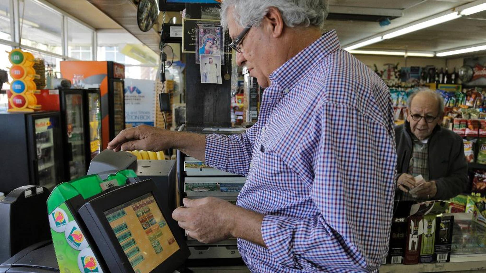 Farouk Tawfik sells Powerball lottery tickets at the Time Saver Food Mart Wednesday, Feb. 11, 2015, in Tampa, Fla. The Powerball jackpot has climbed to $500 million, making Wednesday night's drawing the fifth largest prize in U.S. history. (AP Photo/Chris O'Meara)