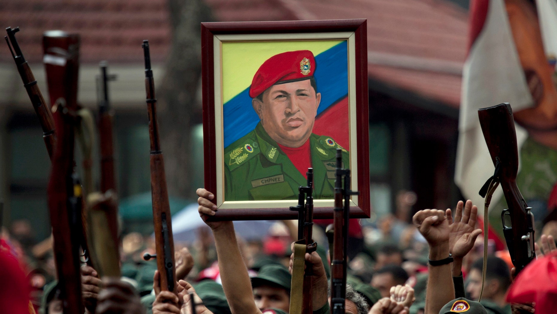 In this April 13, 2010 file photo, members of the National Revolutionary Militia hold up their weapons and a painting of Venezuela's President Hugo Chavez at an event marking the 9th anniversary of Chavez's return to power after a failed 2002 coup, in Caracas, Venezuela. (AP Photo/Ariana Cubillos, File)