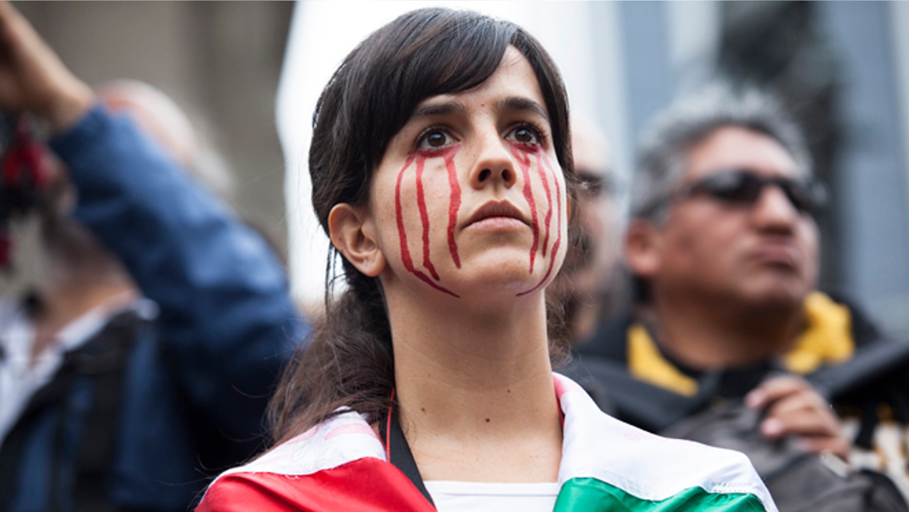 A young woman with fake blood painted on her face watches a protest for 43 missing students from Ayotzinapa Normal school in Mexico City, Mexico. (Photo by Brett Gundlock/Getty Images)