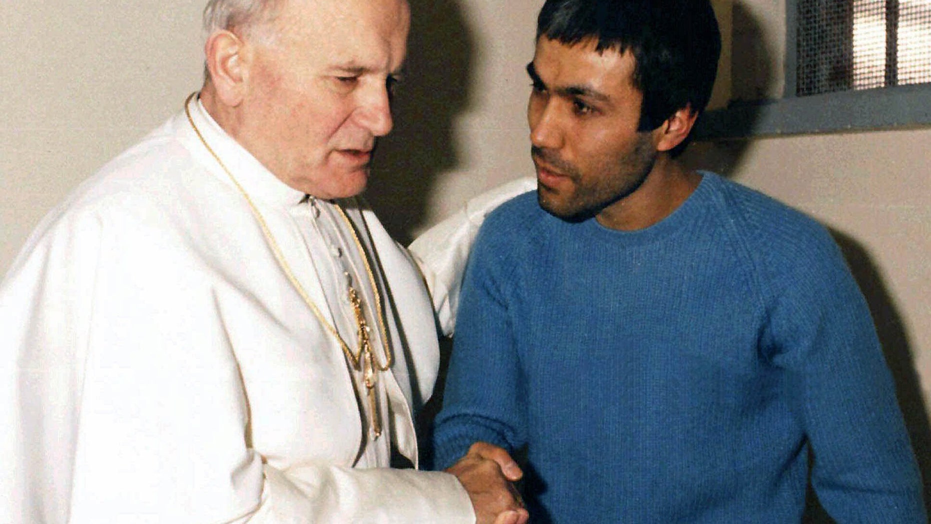 FILE - This Dec. 27, 1983 file photo provided by Vatican newspaper L'Osservatore Romano, shows Pope John Paul II, left, talking with his would-be assassin Mehmet Ali Agca, of Turkey, in Agca's prison cell in Rome. The Turkish gunman who shot Pope John Paul II has changed his story once again, saying in a new autobiography that Iran's late leader Ayatollah Ruhollah Khomeini personally told him to kill the pope. Mehmet Ali Agca writes in "They Promised Me Paradise,'' released Thursday Feb. 1, 2013 in Italy, that he was trained in Iran by Khomeini's forces after escaping from a Turkish prison, and that the Iranian leader himself told him to kill John Paul in the name of God. (AP Photo/Arturo Mari, L'Osservatore Romano)