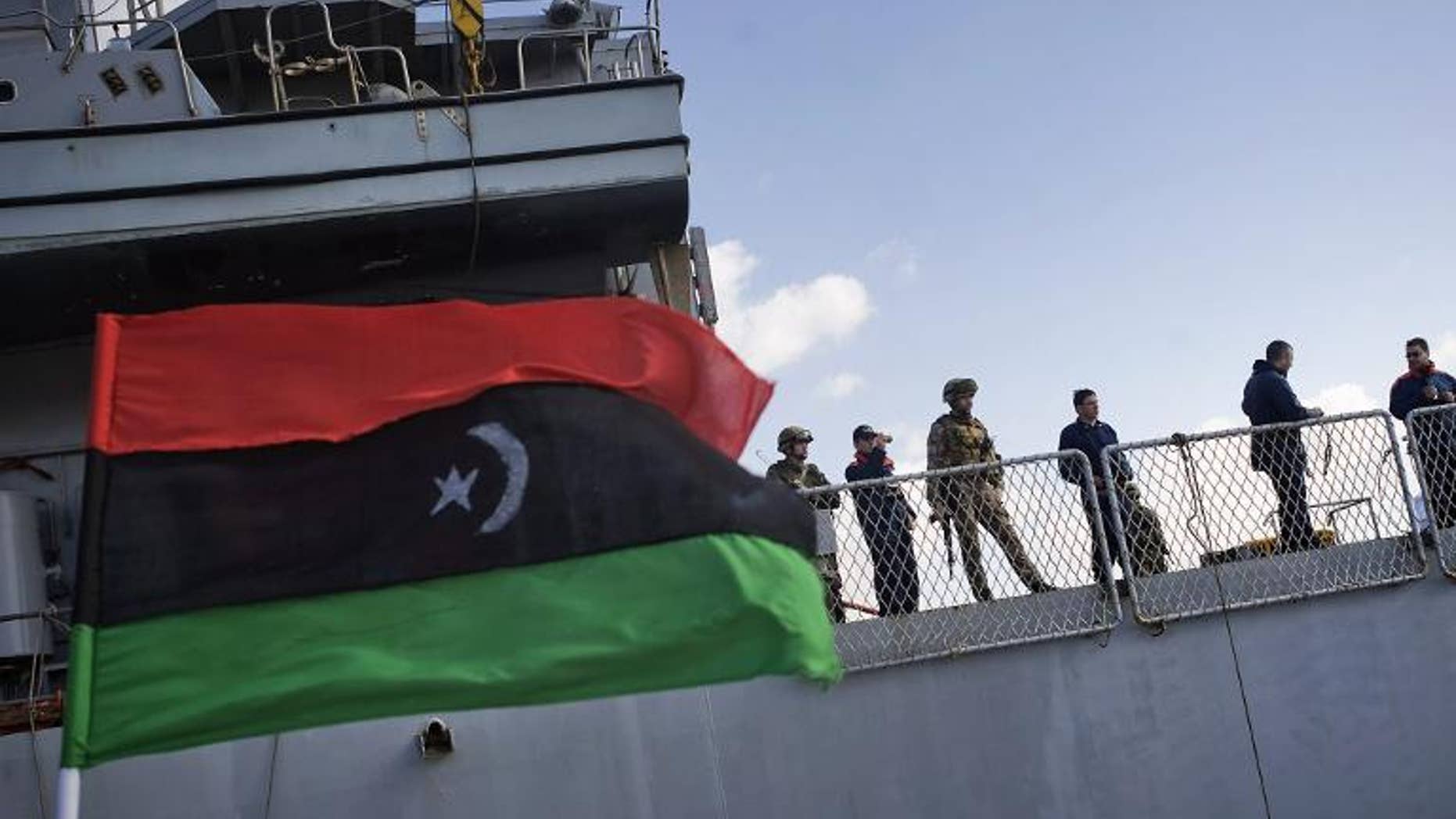 File picture shows an old Libyan national flag fluttering next to the Italian warship in the eastern Libya port of Benghazi on March 7, 2011