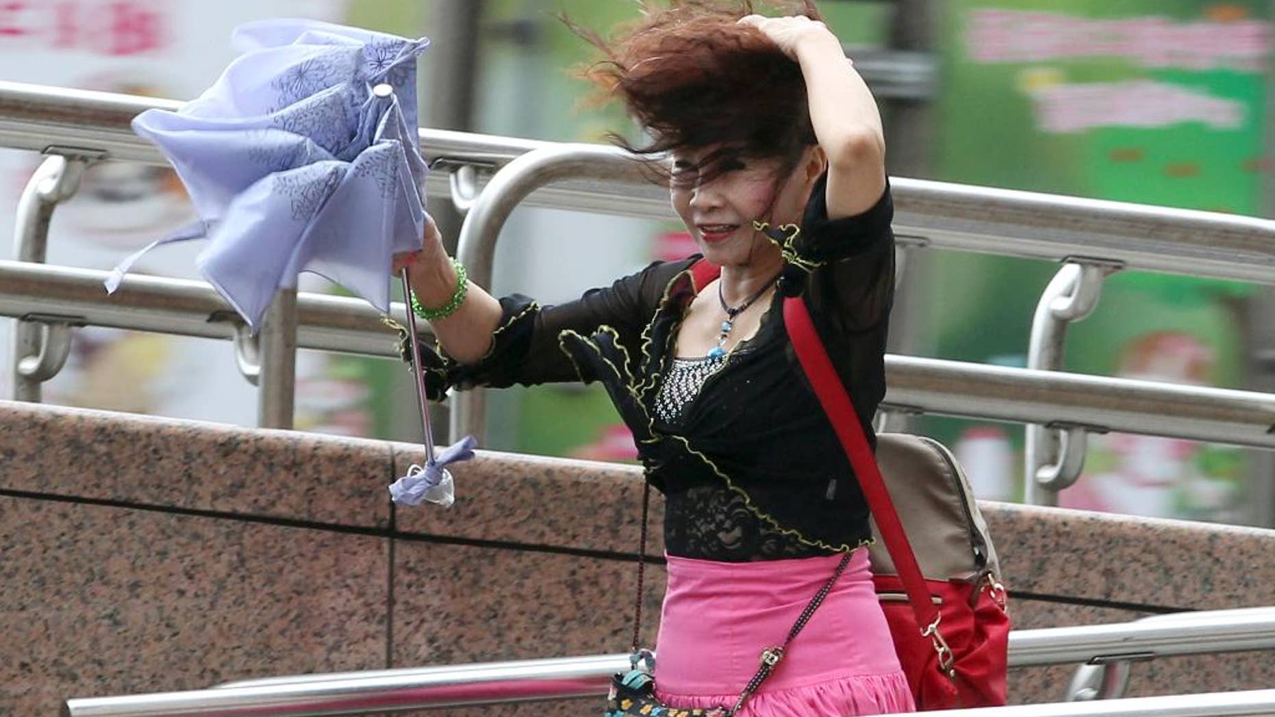 A woman struggles in the wind from Typhoon Nepartak in Taipei, Taiwan, Friday, July 8, 2016. Power was partially restored in Taiwan on Friday after Nepartak slammed into the island's eastern coast with ferocious winds and torrential rains. (Chang Hao-an/Central News Agency via AP)