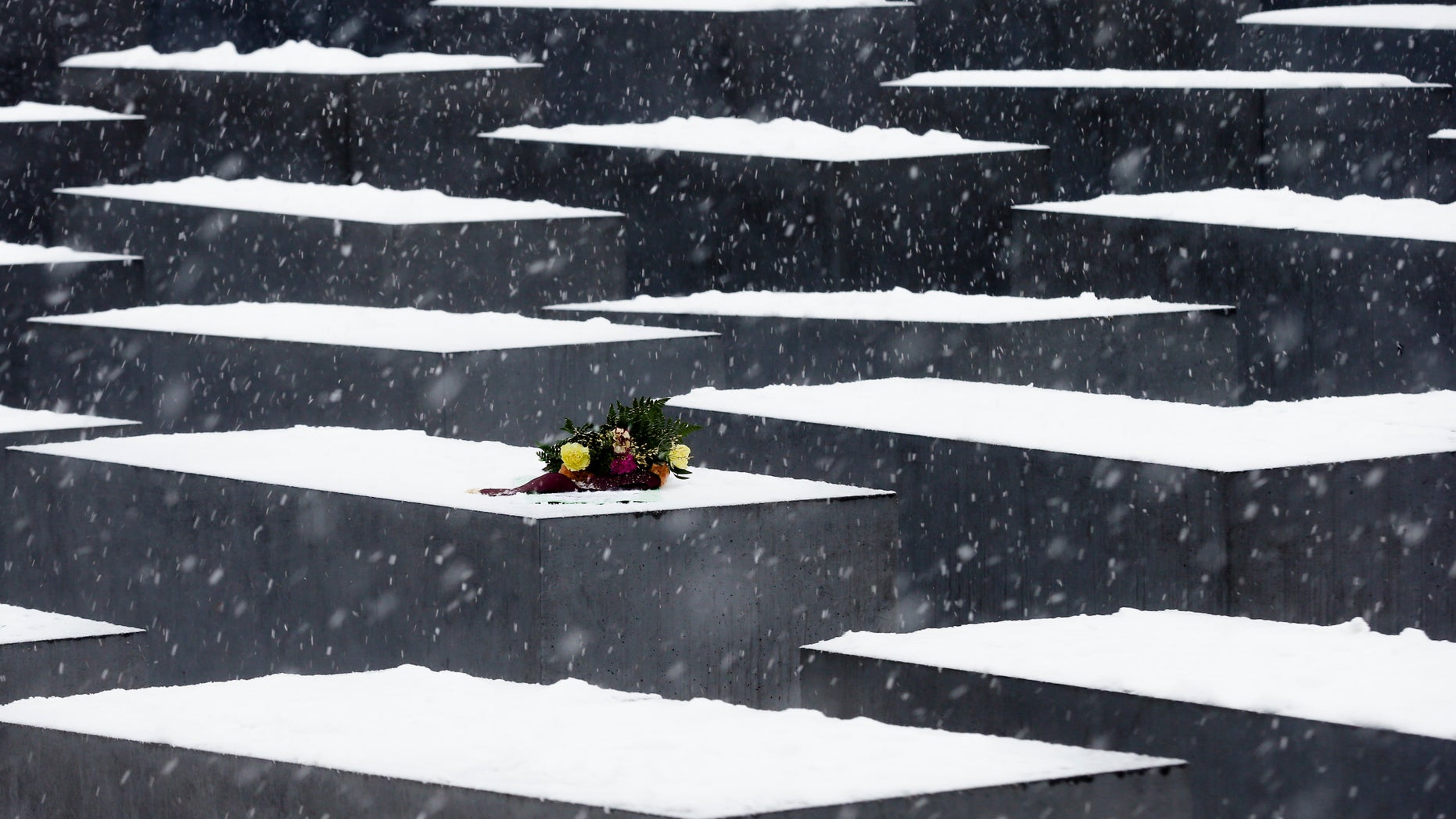 FILE - In this Jan. 27, 2013 file picture, flowers lay on a slab of the Holocaust Memorial to commemorate the victims of the Nazi regime in Berlin. Berlin police say they are considering additional security for Germany’s main Holocaust memorial after an online video appeared to show New Year’s revelers urinated on the site last week. The YouTube video appears to show drunken partygoers relieving themselves and launching fireworks from among the 2,711 concrete blocks commemorating the 6 million Jews killed by the Nazis. The site in the heart of Berlin is close to the Brandenburg Gate where hundreds of thousands of people traditionally ring in the New Year. Police spokesman Thomas Neuendorf said Monday Jan. 6, 2014 that the site was specifically designed to be the open to the public, but that a fence could be erected during big events. (AP Photo/Markus Schreiber,File)