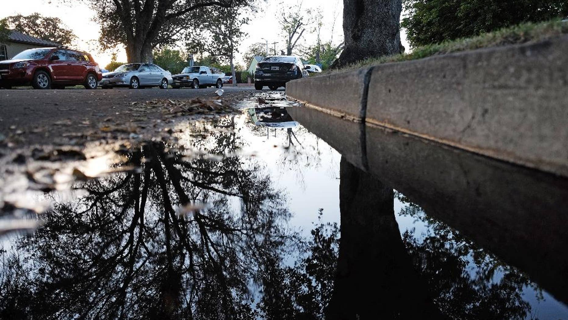 This Sunday, April 13, 2015 photo shows water from a leaking pipe flowing along the curbside of a street in Los Angeles. Southern California's water wholesaler is considering a proposal that would reduce the amount of water it delivers to more than two dozen cities and agencies in the wake of an ongoing drought. A board committee of the Metropolitan Water District meets Monday, April 13, to mull a plan to cut water deliveries by 15 percent beginning this summer. (AP Photo/Richard Vogel)