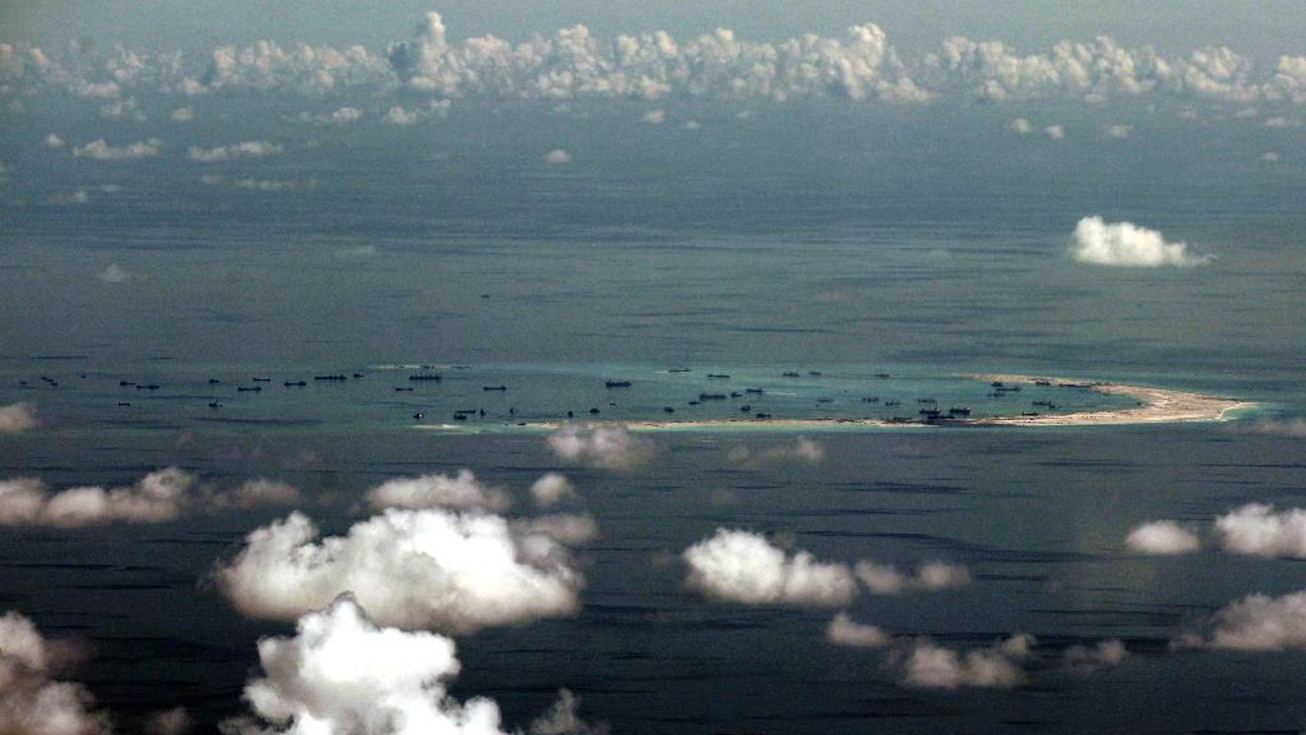 FILE - In this May 11, 2015, file photo, this aerial photo taken through a glass window of a military plane shows China's alleged on-going reclamation of Mischief Reef in the Spratly Islands in the South China Sea. China will complete land reclamation projects on its disputed South China Sea territorial claims as planned within "upcoming days," the Foreign Ministry said Tuesday, June 16, 2015. (Ritchie B. Tongo/Pool Photo via AP)