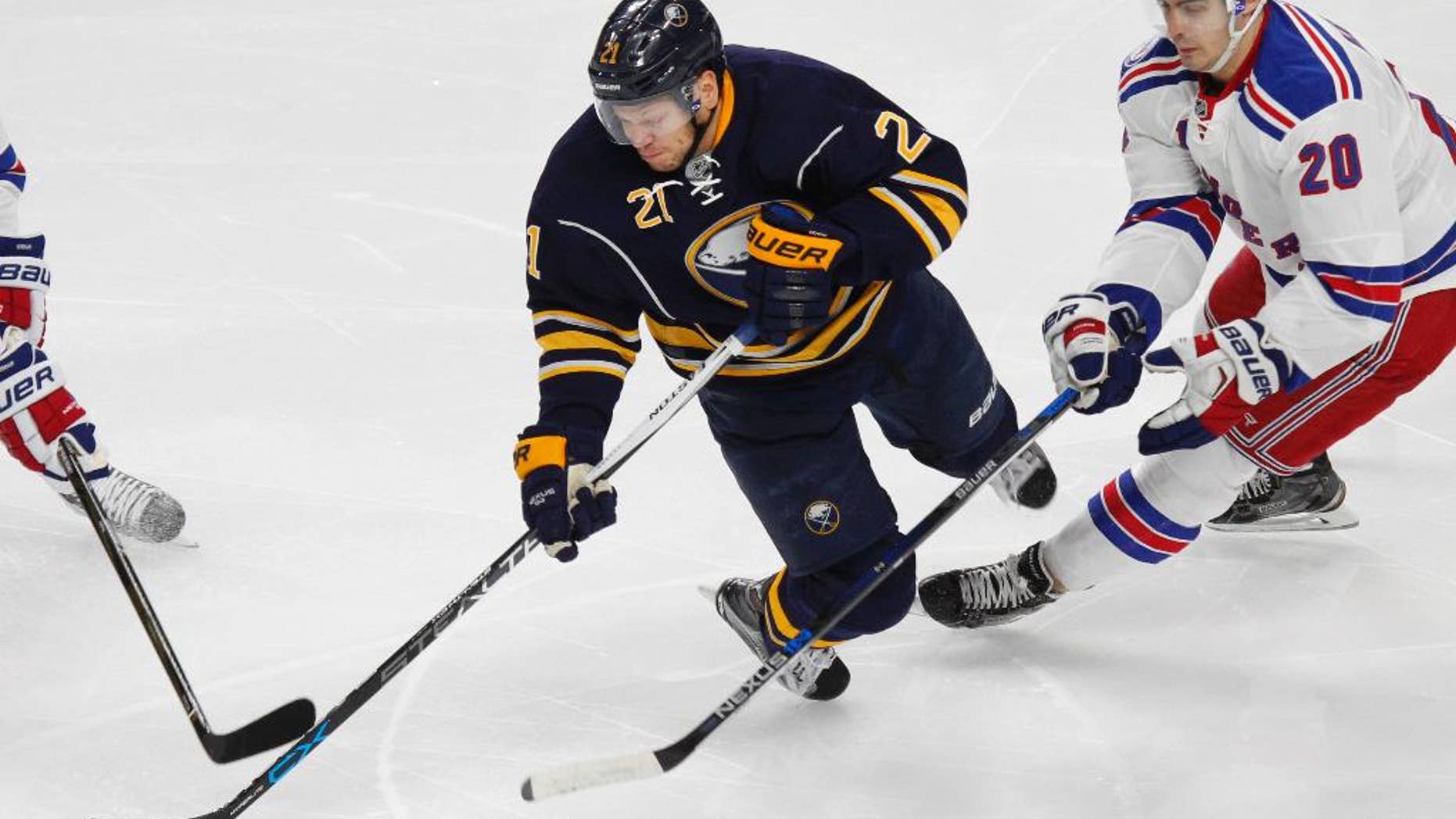 FILE - In this Dec. 1, 2016, file photo, Buffalo Sabres forward Kyle Okposo (21) is tripped up New York Rangers forward Derek Stepan (20) during an NHL hockey game in Buffalo, N.Y. Okposo has spent the past three days in a Buffalo hospital undergoing a battery of tests to determine an undisclosed illness that has sidelined him for more than a week. A person with direct knowledge of Okposo's status confirmed to The Associated Press on Wednesday, April 5, that the player is in the neuro surgical intensive care unit at Buffalo General Hospital. The person spoke on the condition of anonymity because the Sabres have not revealed Okposo has been hospitalized. (AP Photo/Jeffrey T. Barnes, File)