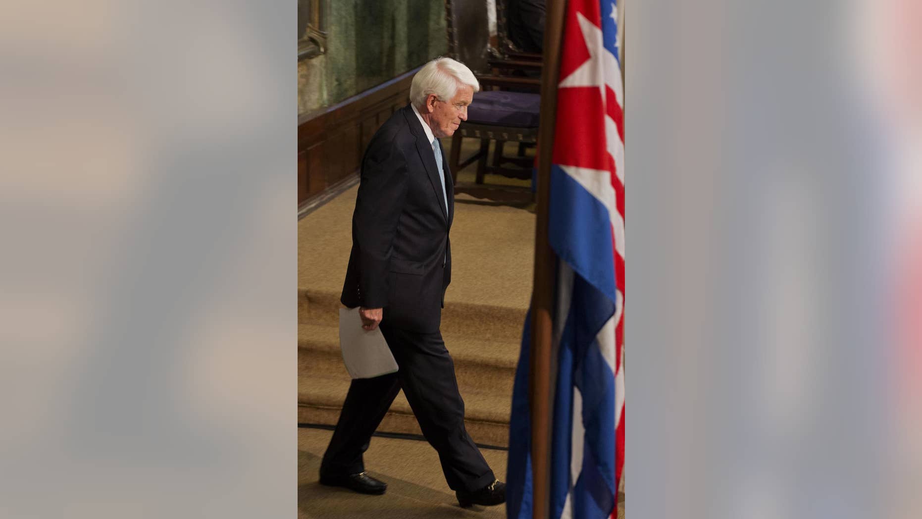 U.S. Chamber of Commerce President and CEO Thomas Donohue walks in front of the Cuban and US flags before a conference at the auditorium of the University in Havana, Cuba, Thursday, May 29, 2014. Donahue urged Cuba to deepen economic reforms on the island, and the US to take steps to normalize relations with the Caribbean nation. (AP Photo/Ramon Espinosa)