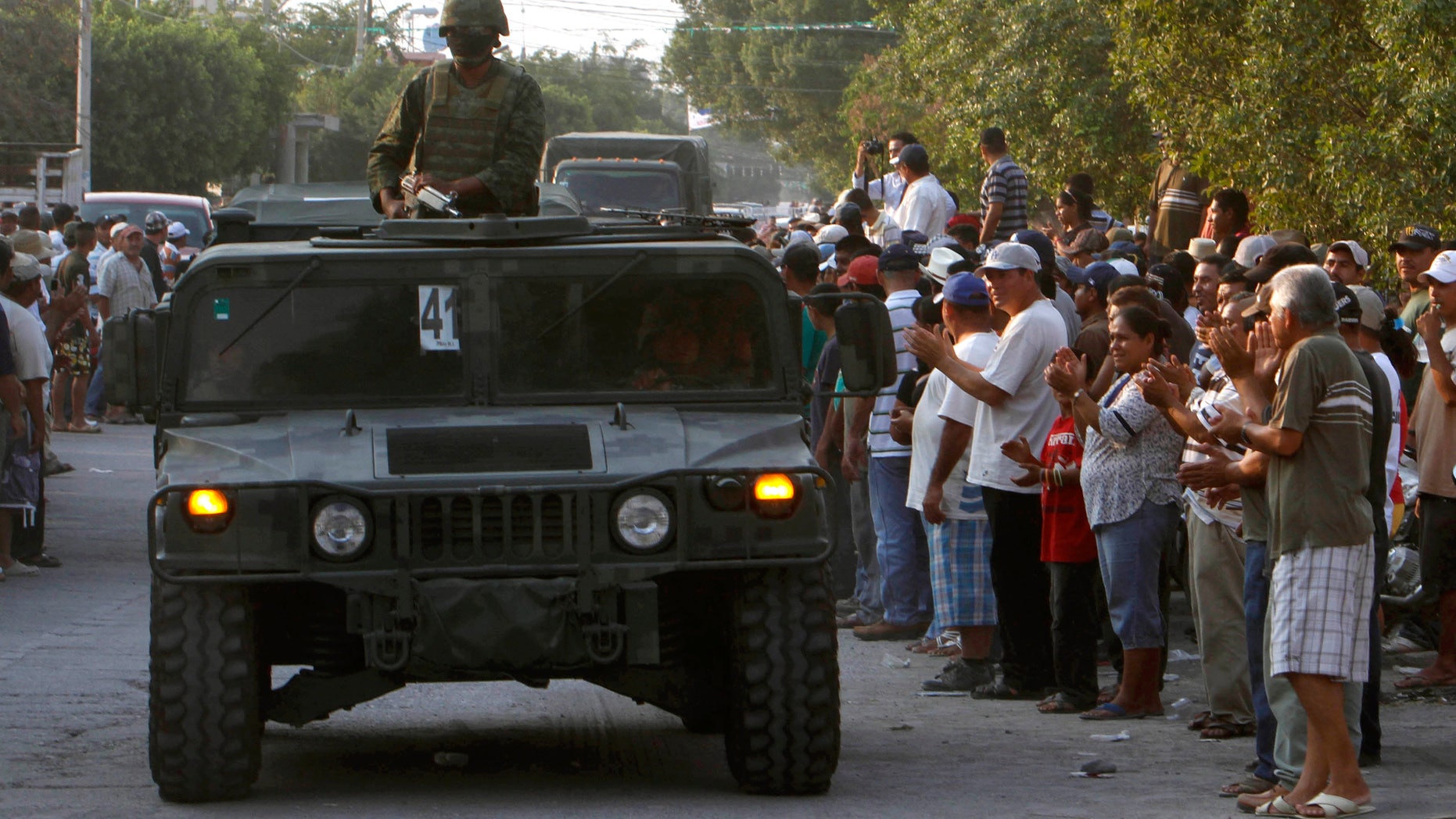 Mexican army soldiers enter the town of La Ruana, Michoacan, Mexico, Monday, May 20, 2013. Residents of western Mexico towns who endured months besieged by a drug cartel are cheering the arrival of hundreds of Mexican army troops. Hundreds of people in the state of Michoacan have taken up arms to defend their villages against drug gangs, a vigilante movement born of frustration at extortion, killings and kidnappings in a region wracked by violence. (AP Photo/Marco Ugarte)