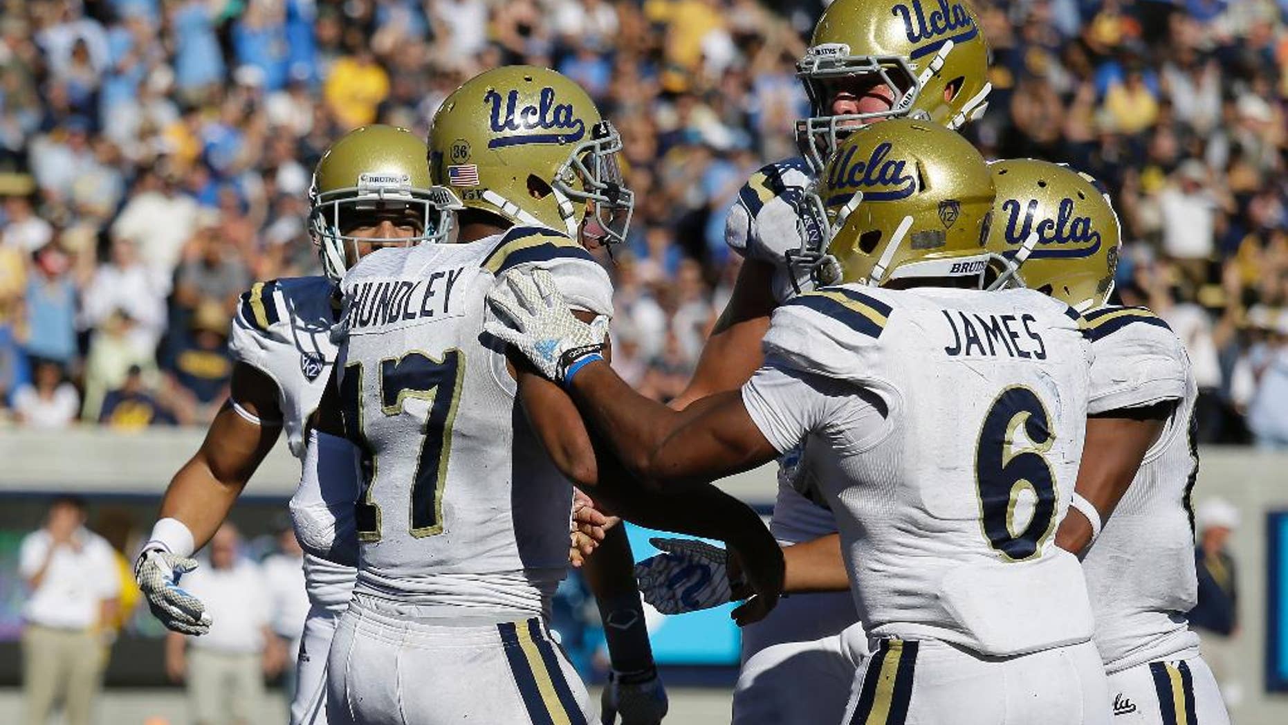 UCLA quarterback Brett Hundley (17) is greeted by his teammates after scoring a touchdown during the third quarter of an NCAA college football game against California on Saturday, Oct. 18, 2014, in Berkeley, Calif. At right is UCLA running back Jordon James (6).UCLA won 36-34. (AP Photo/Eric Risberg)