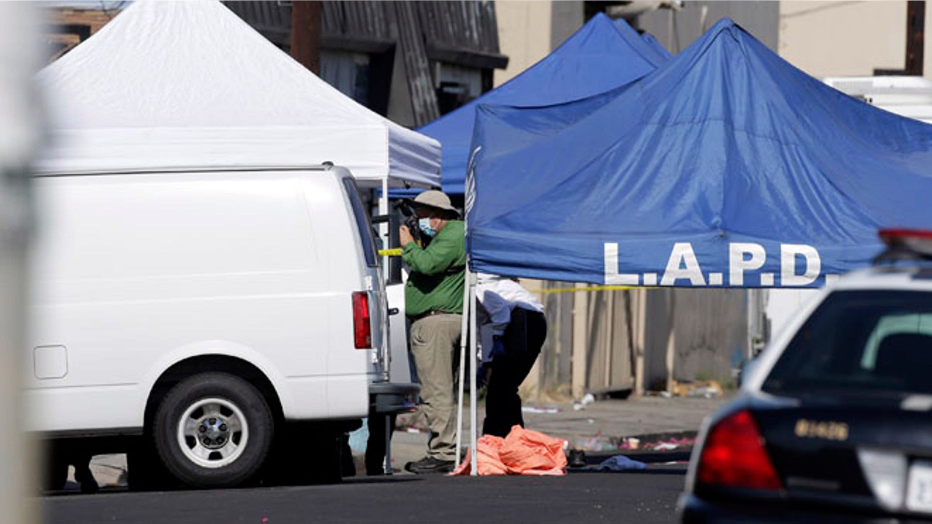 An LAPD investigator photographs a crime scene, where three children were been found dead inside a car.