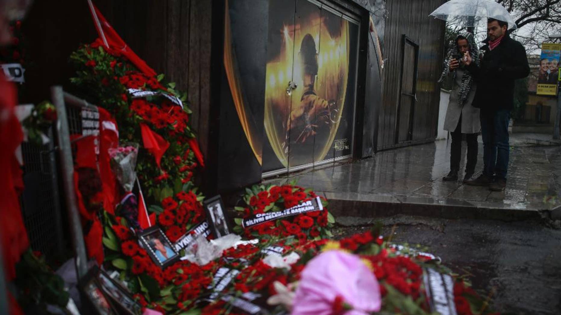 People look at floral tributes left outside the nightclub for the victims of the gunman attack, in Istanbul, Thursday, Jan. 5, 2017. Police on Thursday conducted more raids in their hunt for the gunman that killed 39 people at an Istanbul nightclub, detaining several people at a housing complex in the city's outskirts, the state-run news agency reported. (AP Photo/Emrah Gurel)