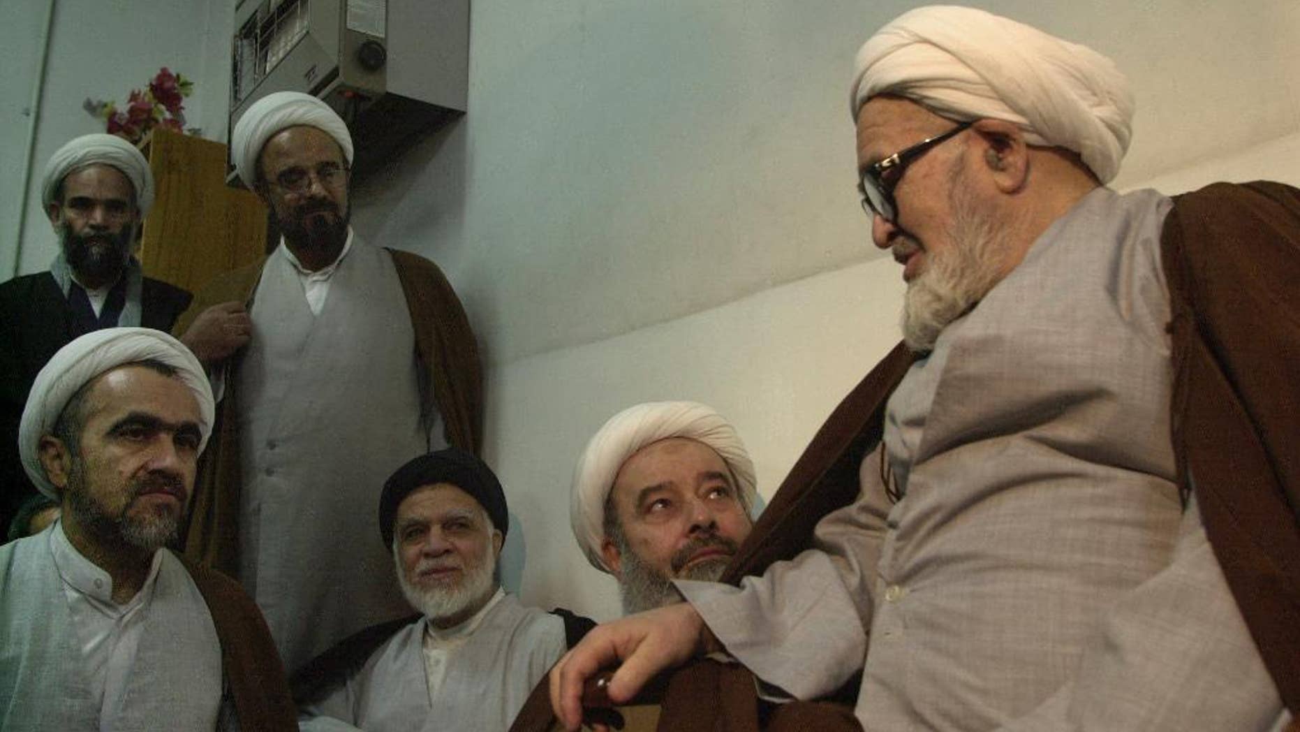 FILE -- In this Jan. 30, 2003 file photo, Grand Ayatollah Hossein Ali Montazeri, Iran's most-senior dissident cleric, right, talks to clerics and his son Ahmad, left, in Qom, 78 miles (125 kilometers) south of Tehran, Iran. Iran's semi-official Fars news agency reported Wednesday, Feb. 22, 2017 that Ahmad Montazeri, the son of late cleric Grand Ayatollah Hossein Ali Montazeri, has begun serving a six-year prison term. In November, 2016, a clerical court sentenced Ahmad Montazeri to six years in prison for publishing a tape recording of his father condemning the execution of thousands of prisoners in 1988 at the end of the country's protracted war with Iraq. (AP Photo/Vahid Salemi, File)