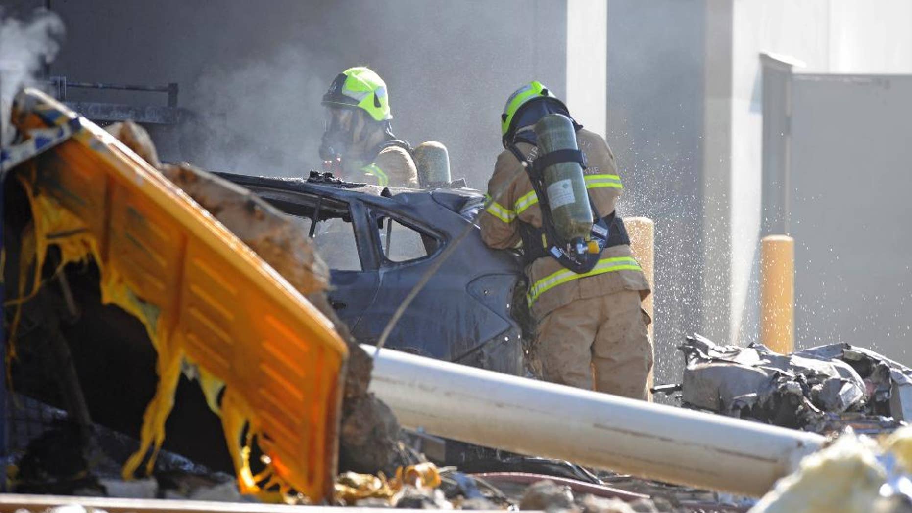 Emergency personnel work at a light plane crashed in Melbourne, Australia, Tuesday, Feb. 21, 2017. The plane crashed into a shopping mall, officials said. (Joe Castro/AAP Image via AP)