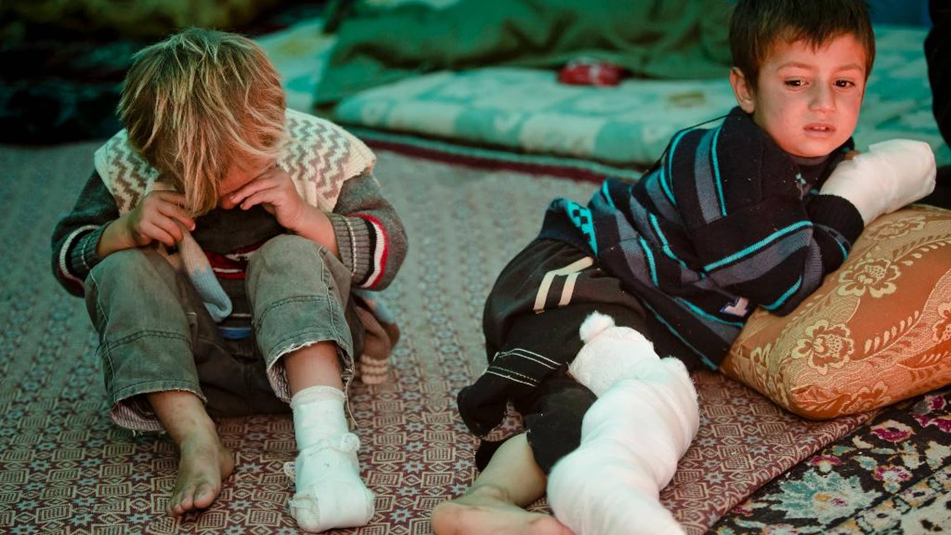 Mahmut Munir, 8 years-old, right, a Syrian Kurdish refugee boy from Kobani and his 5 year-old brother Mahmut, left, who were injured along with other family members in a mortar attack by forces of the Islamic State group sits in a tent at a camp in Suruc, on the Turkey-Syria border Wednesday, Nov. 19, 2014. Kobani, also known as Ayn Arab, and its surrounding areas, has been under assault by extremists of the Islamic State group since mid-September and is being defended by Kurdish fighters. (AP Photo/Vadim Ghirda)