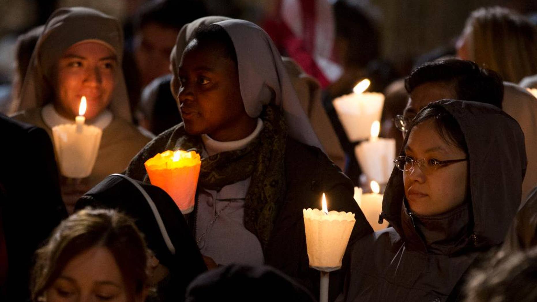 Faithful attend the Via Crucis (Way of the Cross) torchlight procession celebrated by Pope Francis in front of the Colosseum on Good Friday in Rome, Friday, April 18, 2014. (AP Photo/Gregorio Borgia)
