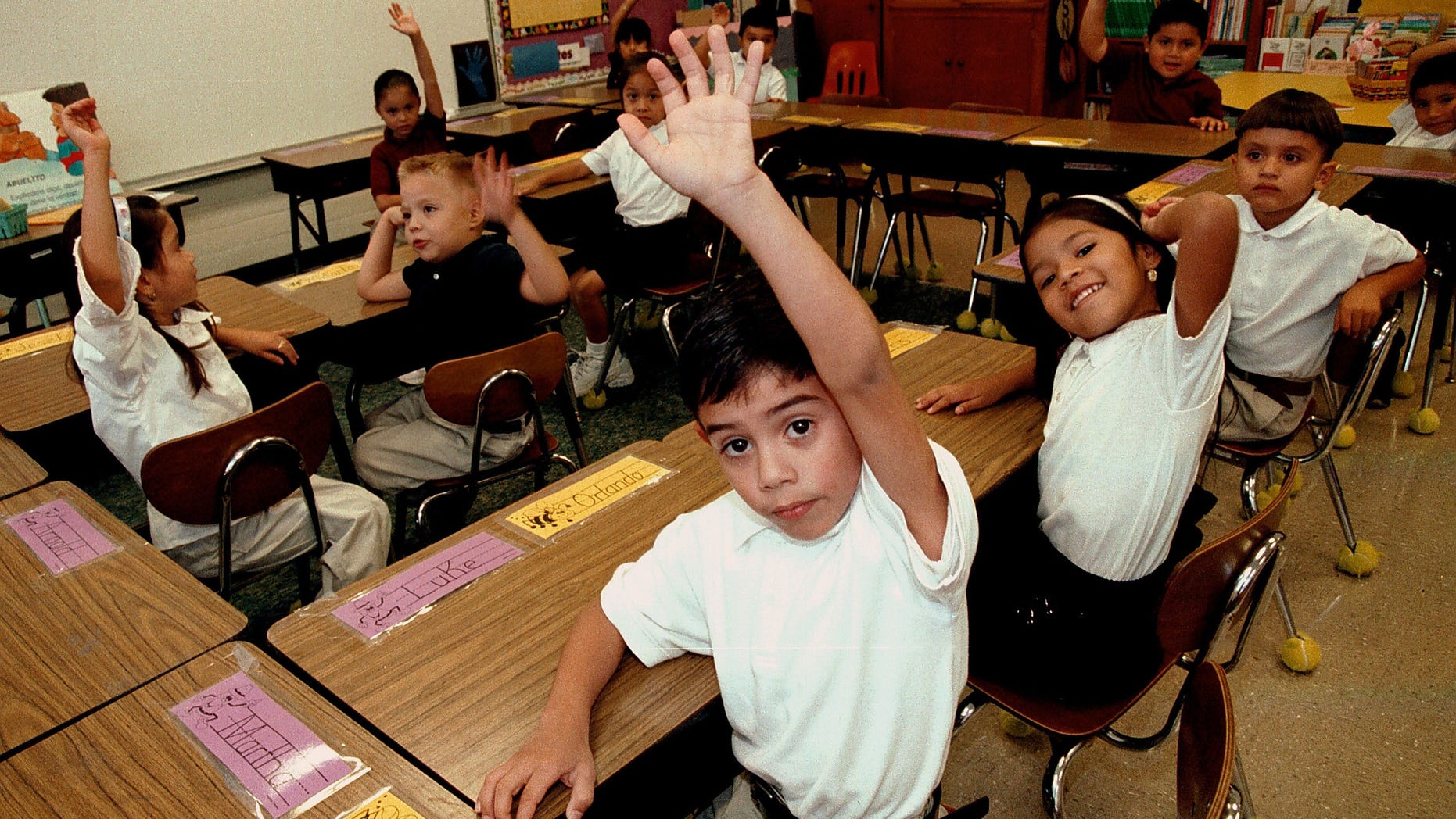 Hispanic students raise their hands to answer a question during a class taught in Spanish at Birdwell Elementary School September 11, 2003 in Tyler, Texas. (Photo by Mario Villafuerte/Getty Images)