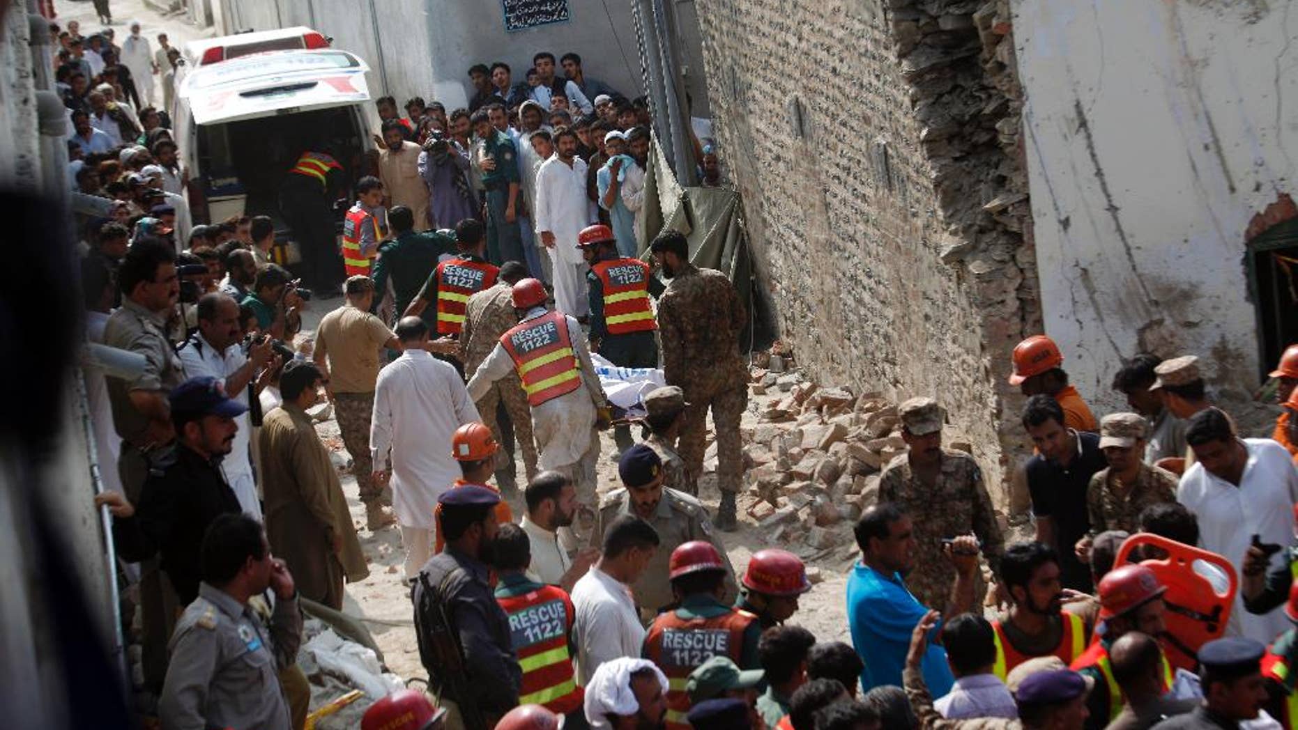 Pakistani rescue workers recover dead bodies from the rubble of the site of a suicide bombing, in Shadi Khan, some 80 kilometers (50 miles) northwest from the Pakistani capital, Sunday, Aug. 16, 2015. A pair of suicide bombers detonated their explosives at the home of an anti-Taliban provincial minister, killing him and more than a dozen others in eastern Pakistan, officials said. (AP Photo/Anjum Naveed)