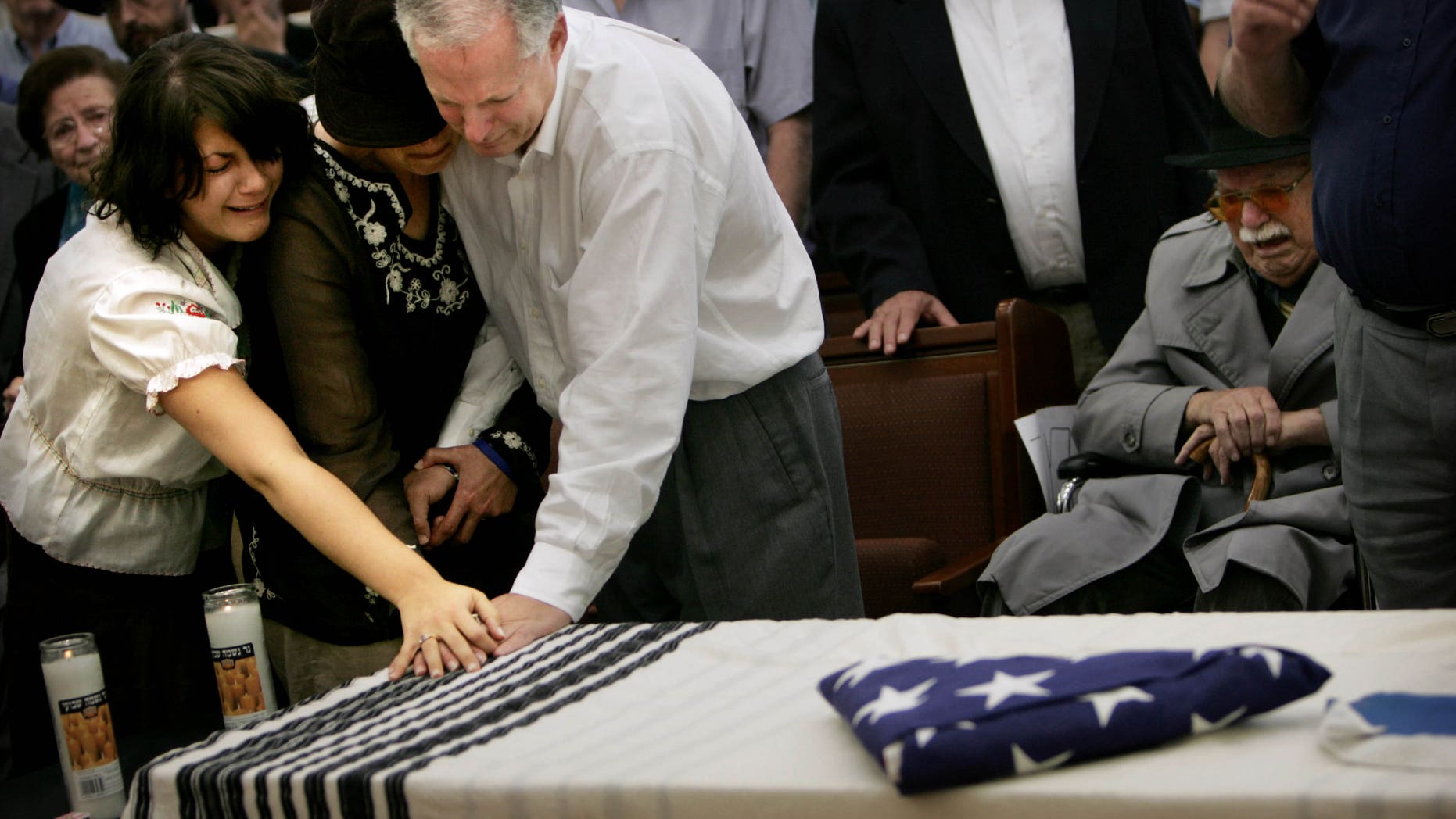 FILE - In this May 15, 2006 file photo, parents of American teenager Daniel Wultz, Tuly, and Cheryl, and his sister Amanda, left, touch his coffin, covered by a Jewish prayer shawl and a folded American flag, given to the family by the U.S. Ambassador in Israel, during a memorial service at a Jerusalem synagogue before transferring his body to the U.S. for burial. Darshan-Leitner is representing 22 families of people who were killed in Palestinian suicide bombings. The families accuse the government-owned Bank of China, through its U.S. branches, of serving as a key conduit in transfers of money to Hamas and Islamic Jihad, Palestinian groups that have killed hundreds of Israelis. The family of Daniel Wultz, a 16-year-old American who was killed in a 2006 suicide bombing in Tel Aviv carried out by Islamic Jihad, is pursuing a separate but related case against the bank. (AP Photo/Oded Balilty, File)