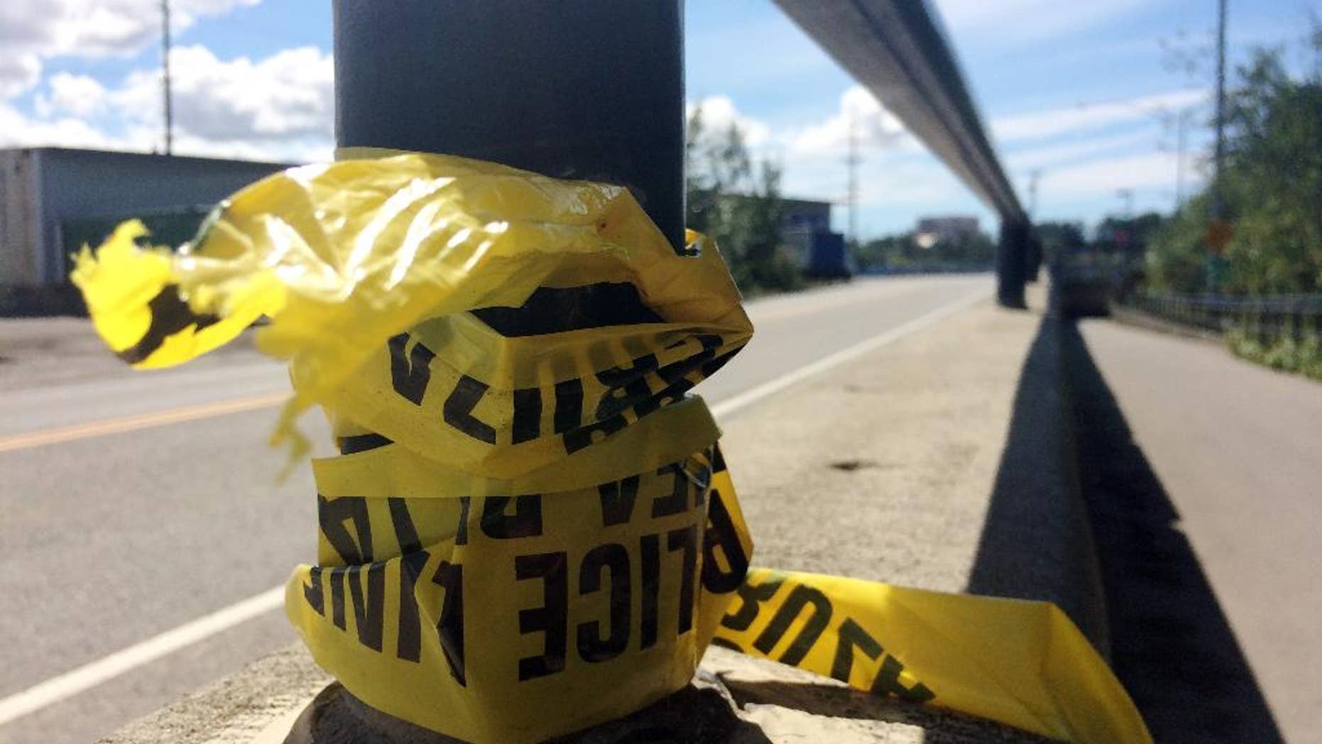 Police tape hangs from a hand rail near where two people were killed on the Ship Creek Trail in downtown Anchorage, Alaska, in July.