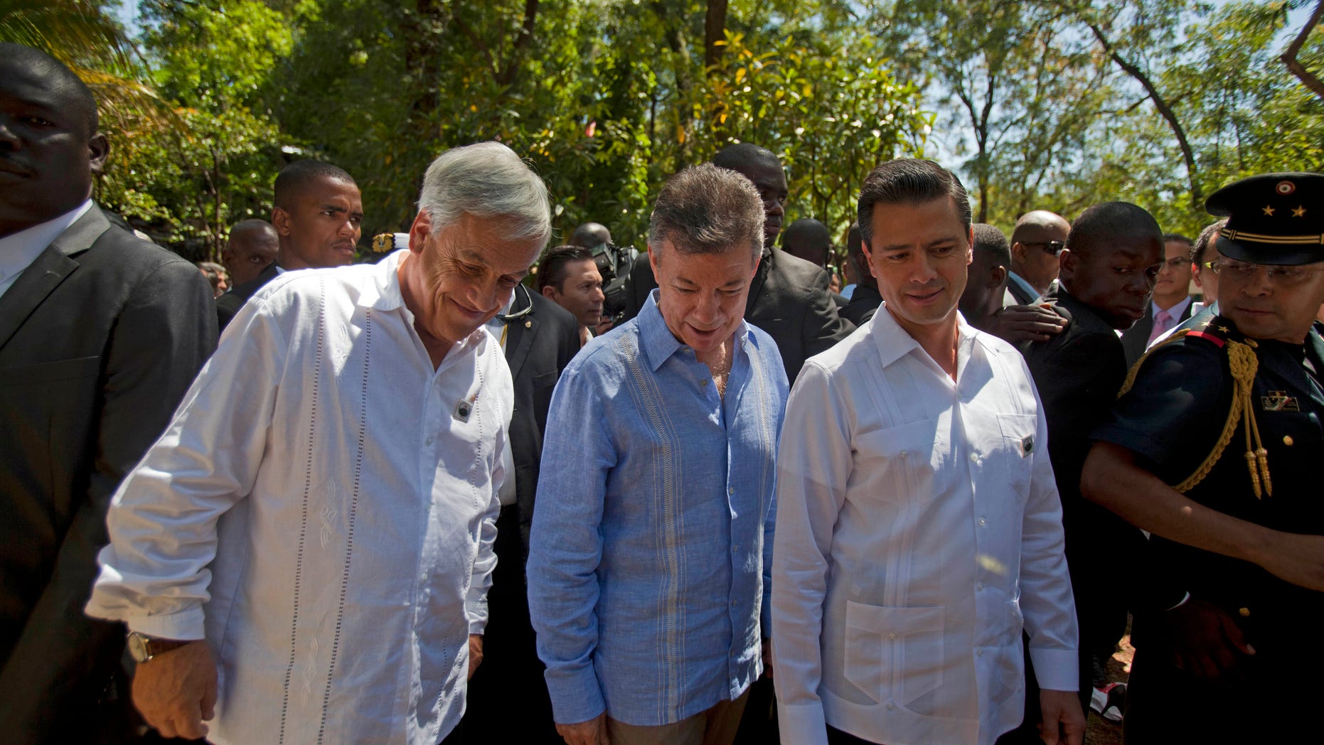 Chile's President Sebastian Pinera, left, Colombia's President Juan Manuel Santos, center, and Mexico's President Enrique Pena Nieto stroll through a hotel garden while taking a break from the Association of Caribbean States regional summit, in Port-au-Prince, Haiti. Friday April 26, 2013. Haiti wrapped up the international summit on Friday that brought together six presidents from the region who all signed an agreement that called for an end to the U.S. embargo against Cuba and to help the region better prepare for disasters. (AP Photo/Dieu Nalio Chery)