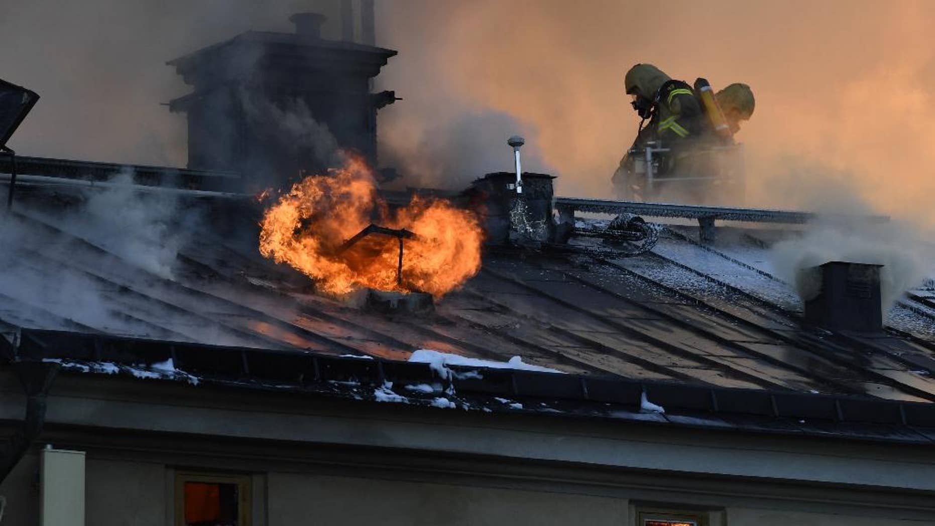 Firefighters try to extinguishing a fire at the Royal Institute of Art in Stockholm, Sweden, Wednesday, Sept. 21, 2016. A fire has started in a building belonging to Stockholm's Royal Institute of Art, sending a plume of smoke over large parts of the Swedish capital. Dozens of firefighters struggled to contain the blaze, which raced through the attic and roof of the building on Skeppsholmen island near downtown Stockholm on Wednesday. There were no reports of injuries. (Anders Wiklund/TT News Agency via AP)