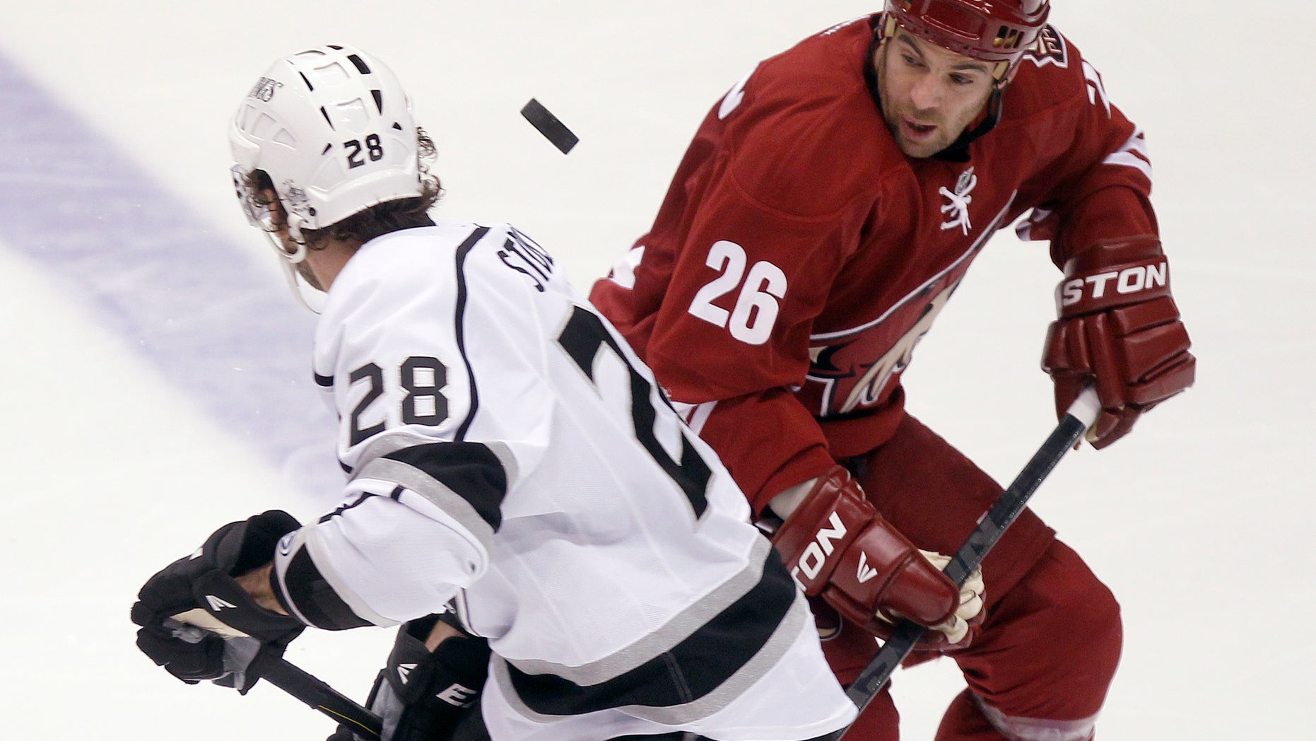 Los Angeles Kings center Jarret Stoll, left, and Phoenix Coyotes left winger Steve Sullivan, right, looks to gain control of a loose puck in the third period of an NHL hockey game Tuesday, April 2, 2013, in Glendale, Ariz. The Coyotes won 3-1. (AP Photo/Paul Connors)
