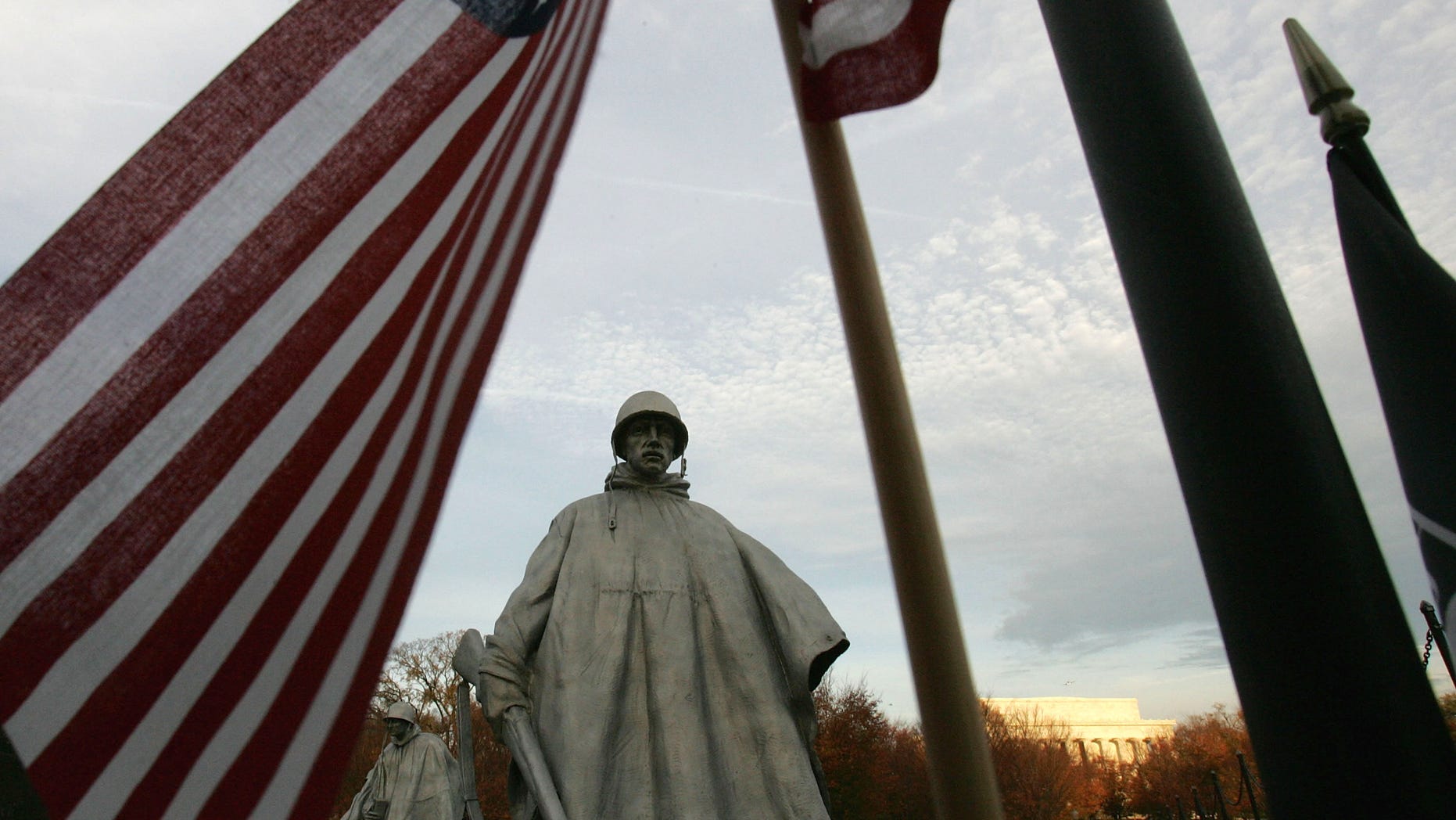 WASHINGTON - NOVEMBER 11: A U.S. flag frames a statue from the Korean War memorial on Veterans Day as visitors pay their respects to the soldiers killed during the war November 11, 2004 in Washington, DC. (Photo by Joe Raedle/Getty Images)
