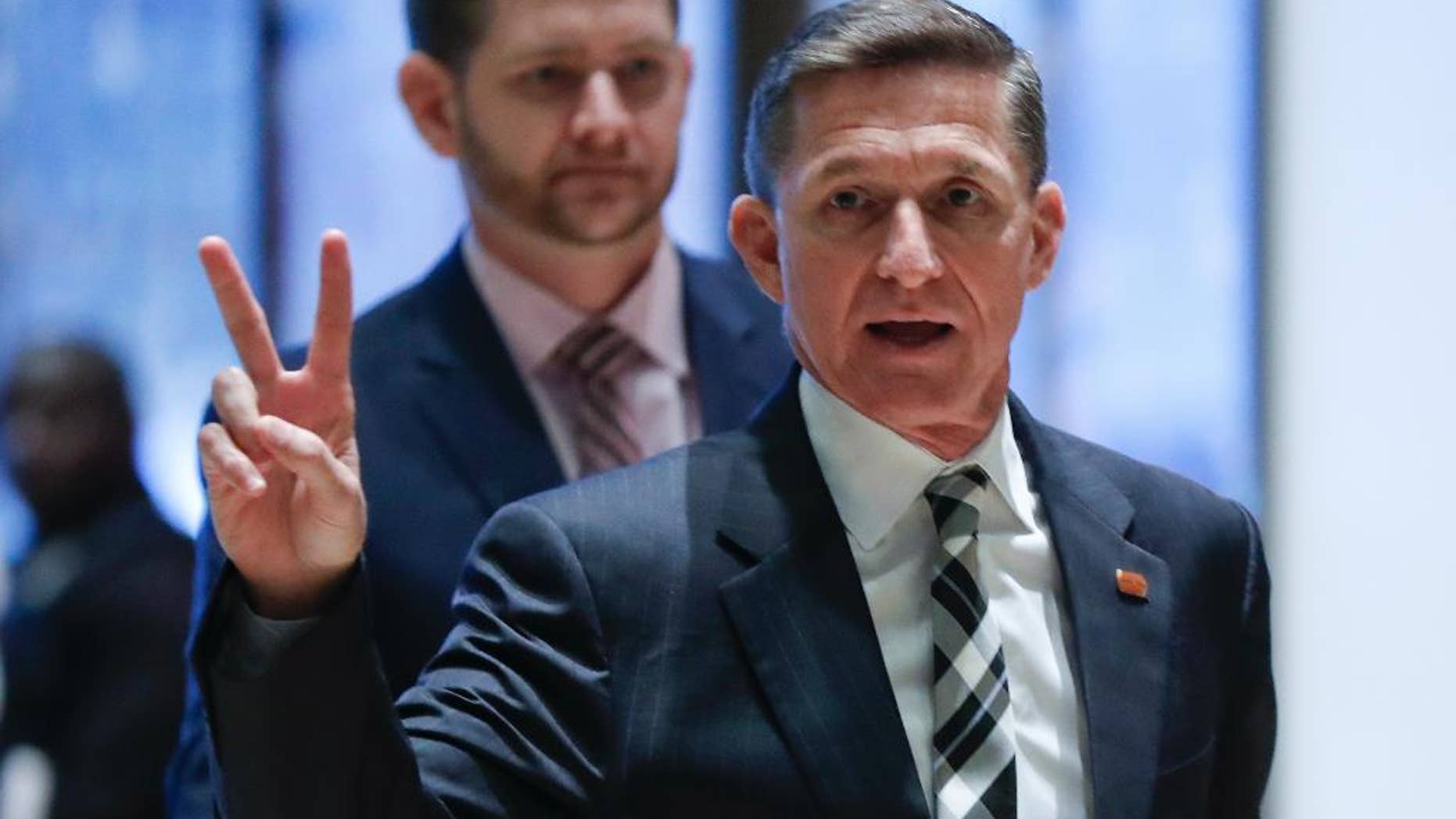 FILE- In this Nov. 17, 2016, file photo, retired Lt. Gen Michael Flynn gestures as he arrives with his son Michael G. Flynn, left, at Trump Tower in New York. Flynn was fired by one American commander-in-chief for insubordination, Now he may removed by another. Flynn resigned as President Donald Trump's national security adviser Monday, Feb. 13, 2017. (AP Photo/Carolyn Kaster, File)