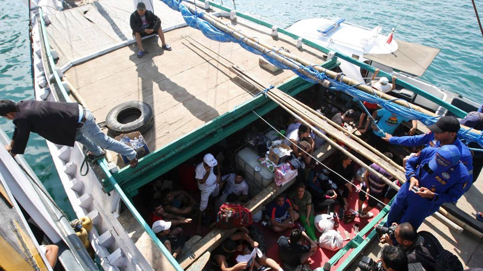 FILE - In this May 12, 2013 file photo, Iranian asylum seekers who were caught in Indonesian waters while sailing to Australia, sit on a boat, at Benoa port in Bali, Indonesia. Australia is in talks to send refugees who try to reach its shores illegally to the Philippines, the immigration minister said in Canberra Australia, Friday, Oct. 9, 2015. Australia refuses to accept any refugees who attempt to reach its shores by boat, and pays Nauru and Papua New Guinea, which has a detention center on Manus Island, to hold them instead. (AP Photo/Firdia Lisnawati)